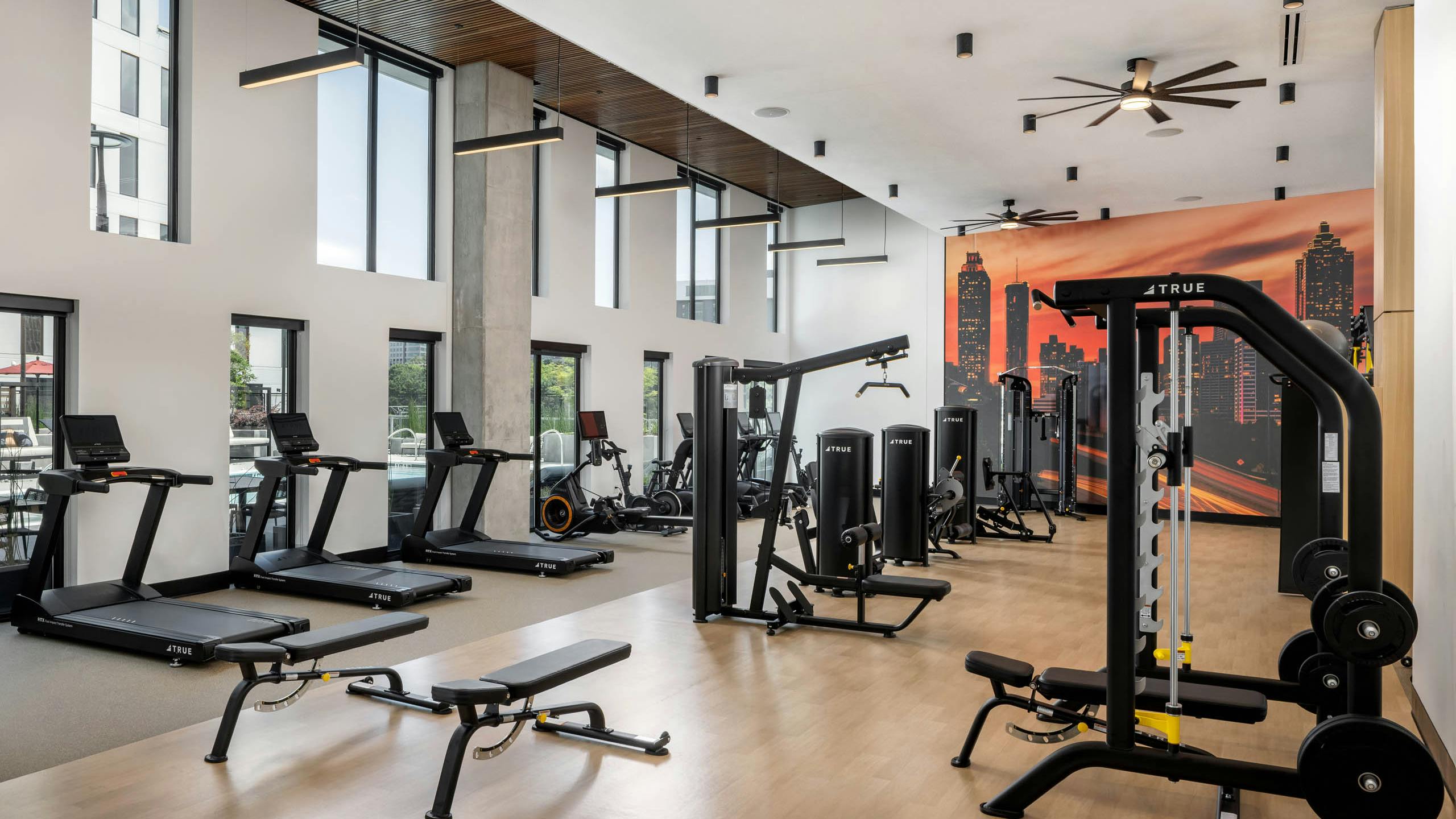 AMLI Atlantic Station’s fitness center with equipment facing a wall of windows.