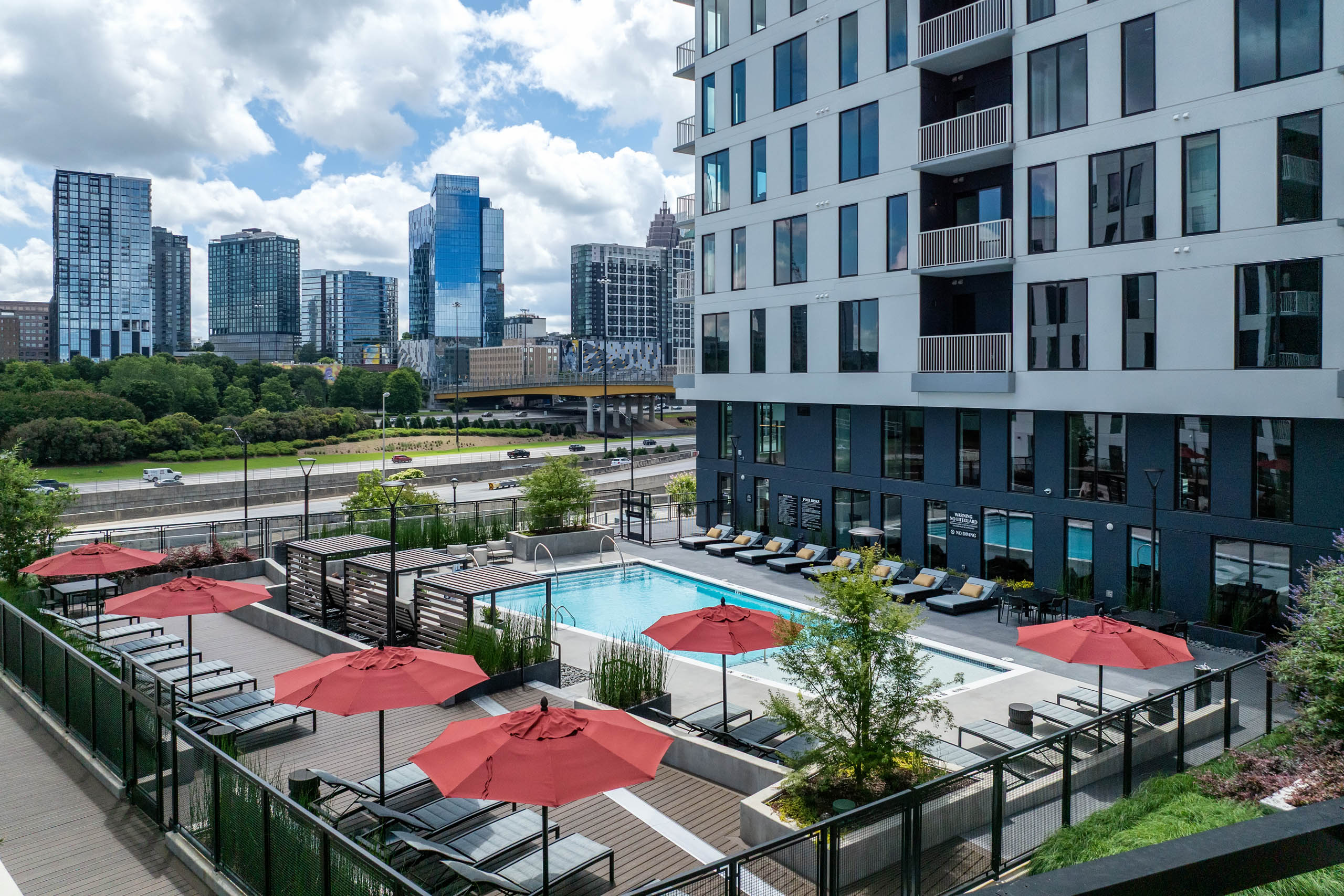 Swimming pool with umbrellas and daytime view of city skyline at AMLI Atlantic Station.