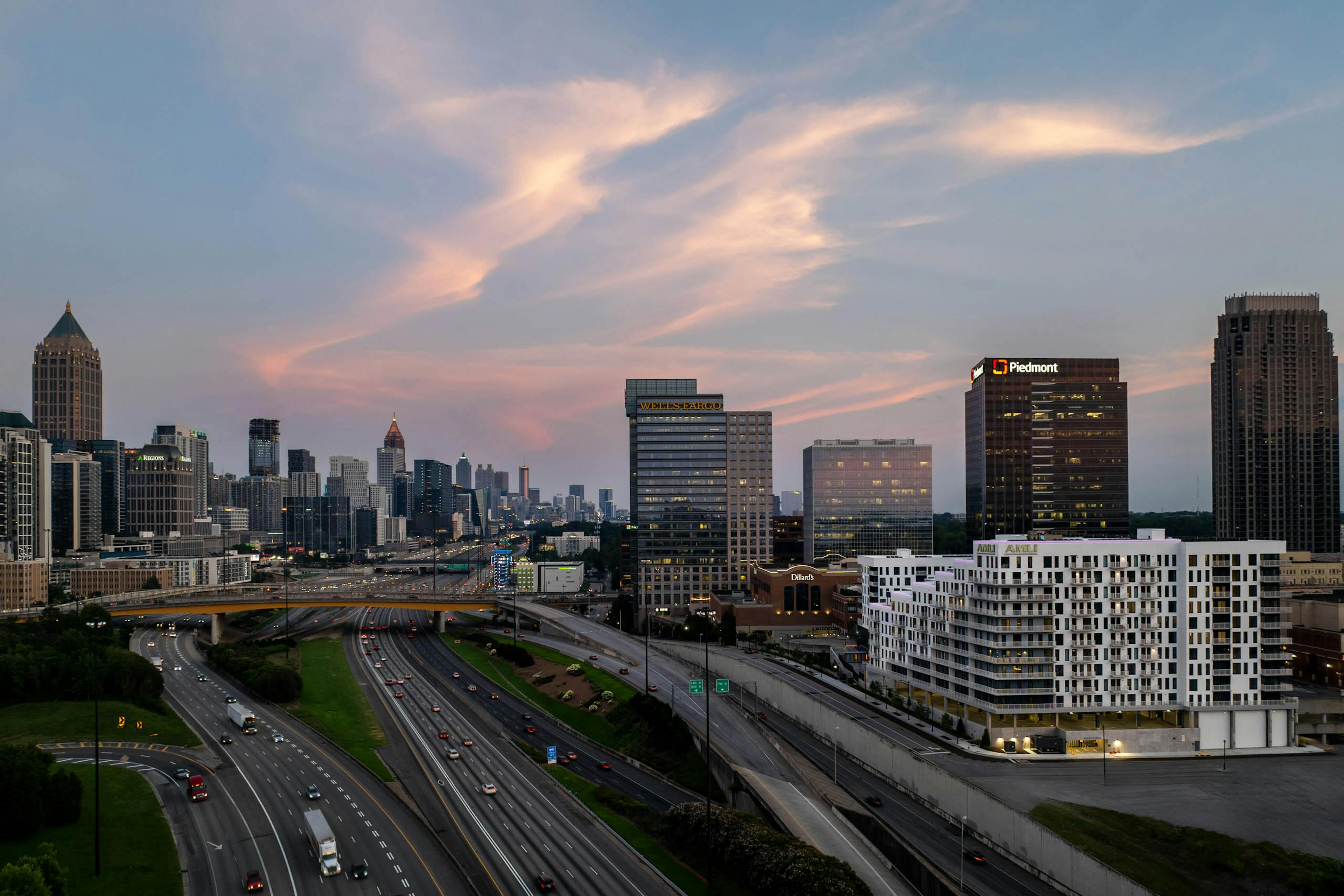 Sunset view of the city skyline over a highway with AMLI Atlantic Station in the foreground.