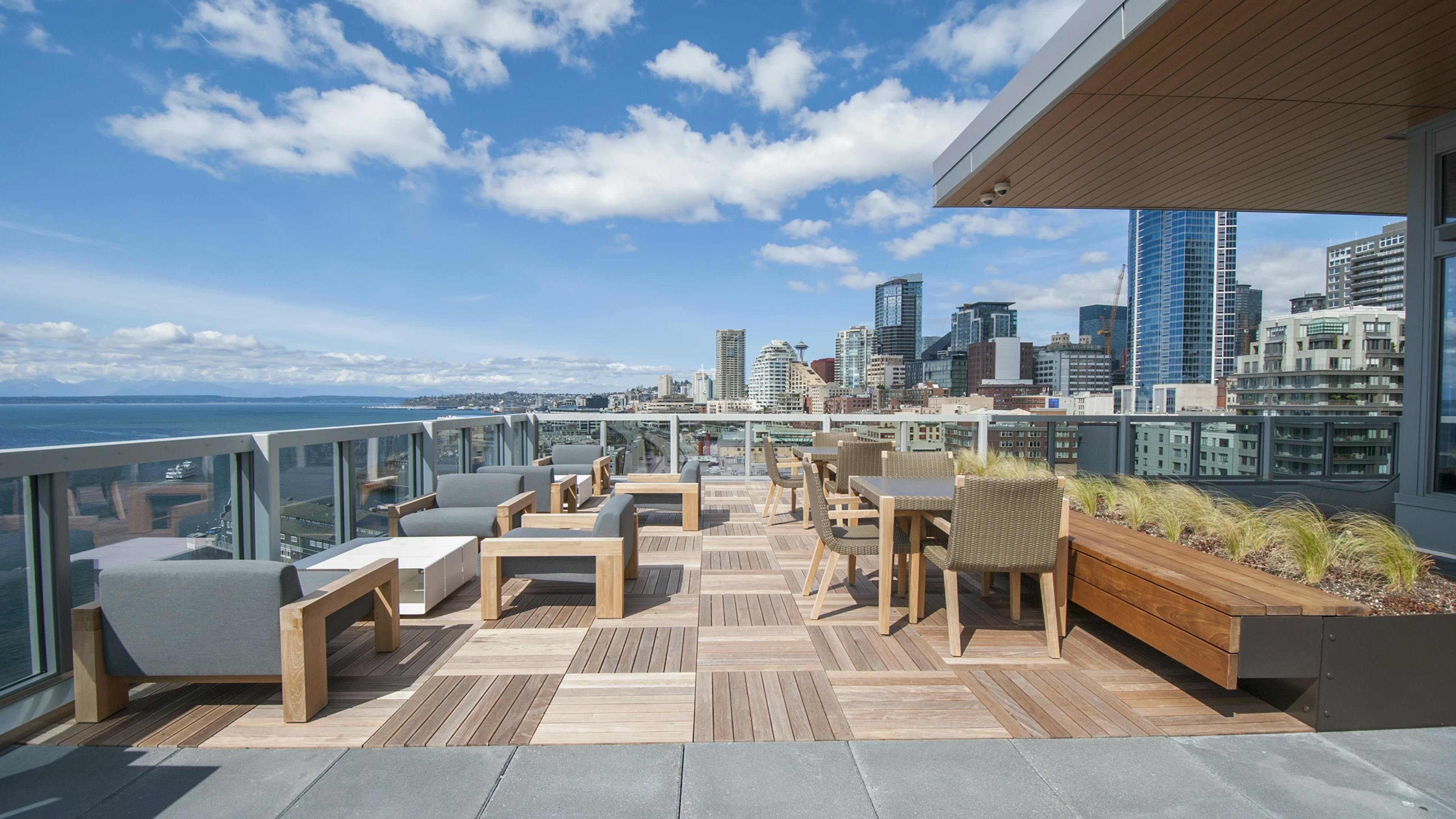 Rooftop deck at AMLI Waterfront apartments with wood furniture, skyline views, bayfront seating, and built-in planters.