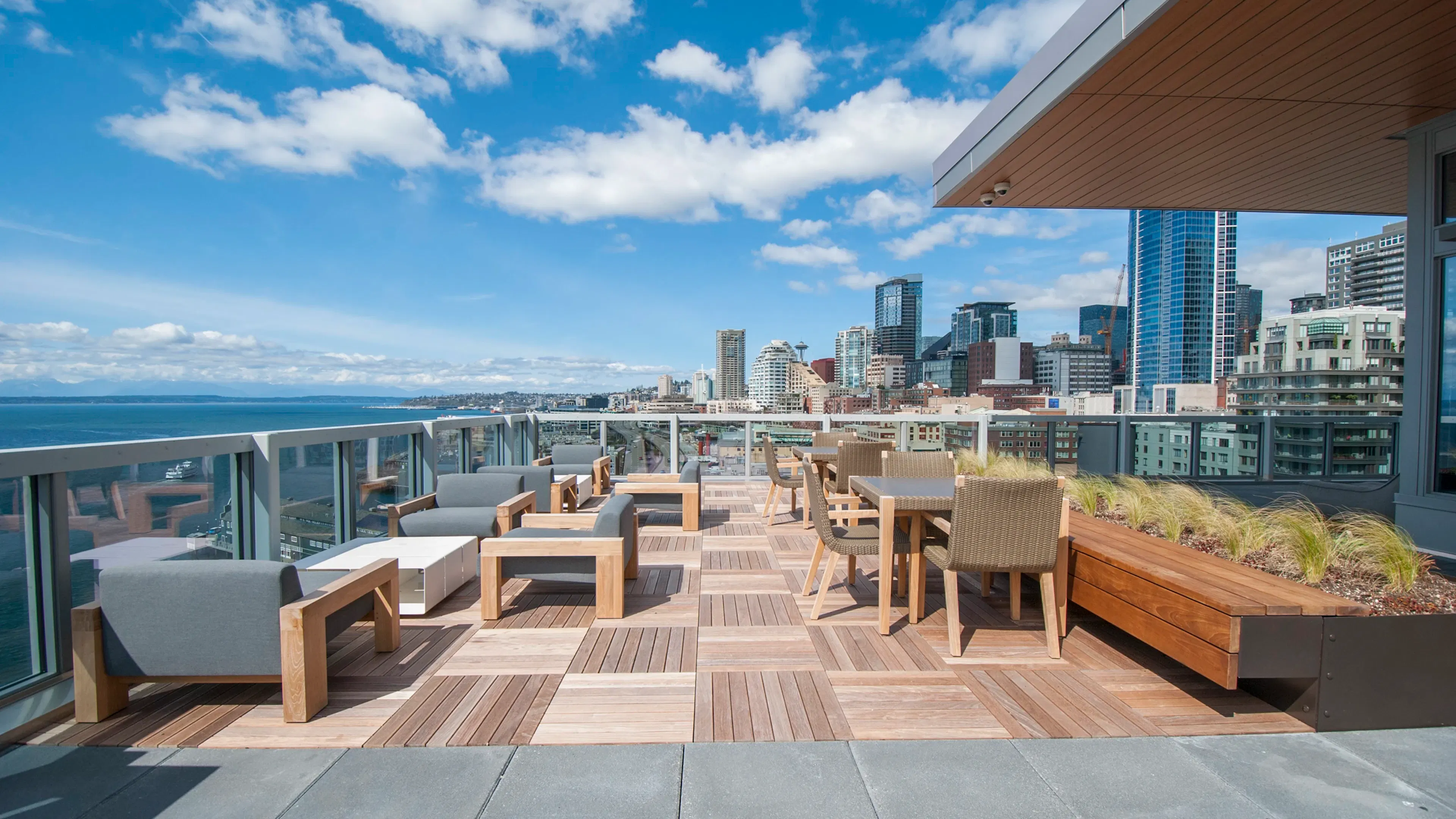 Rooftop deck at AMLI Waterfront apartments with wood furniture, skyline views, bayfront seating, and built-in planters.
