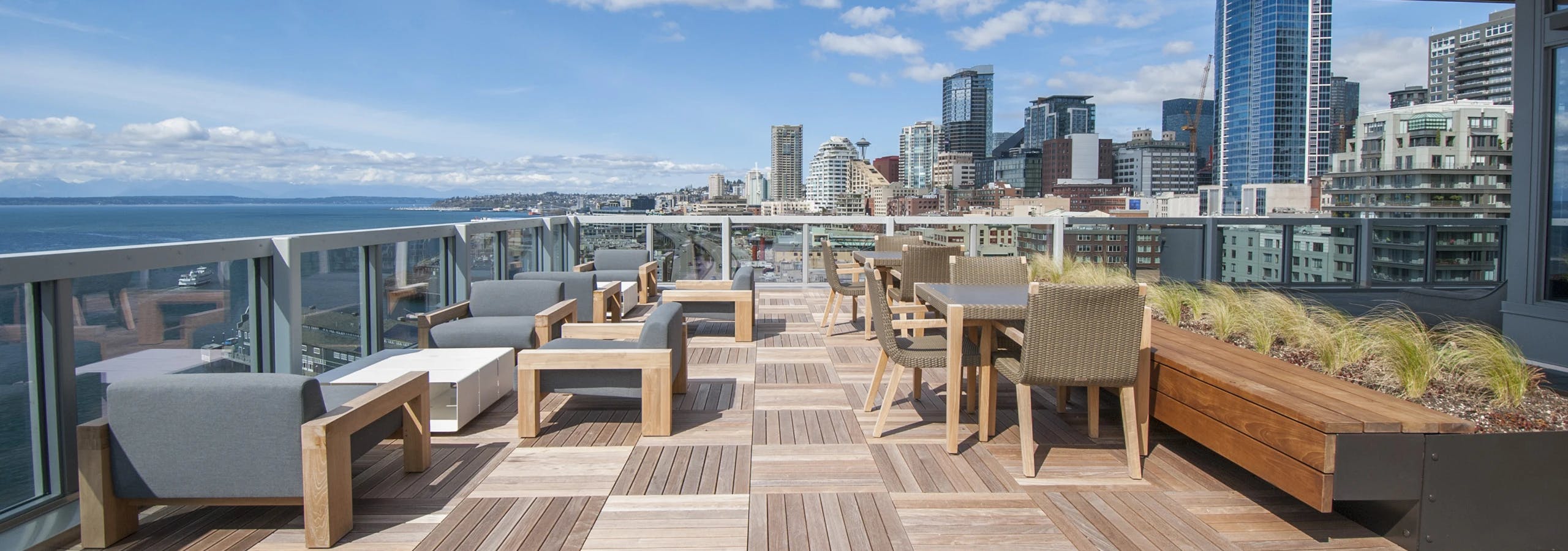 Rooftop deck at AMLI Waterfront apartments with wood furniture, skyline views, bayfront seating, and built-in planters.
