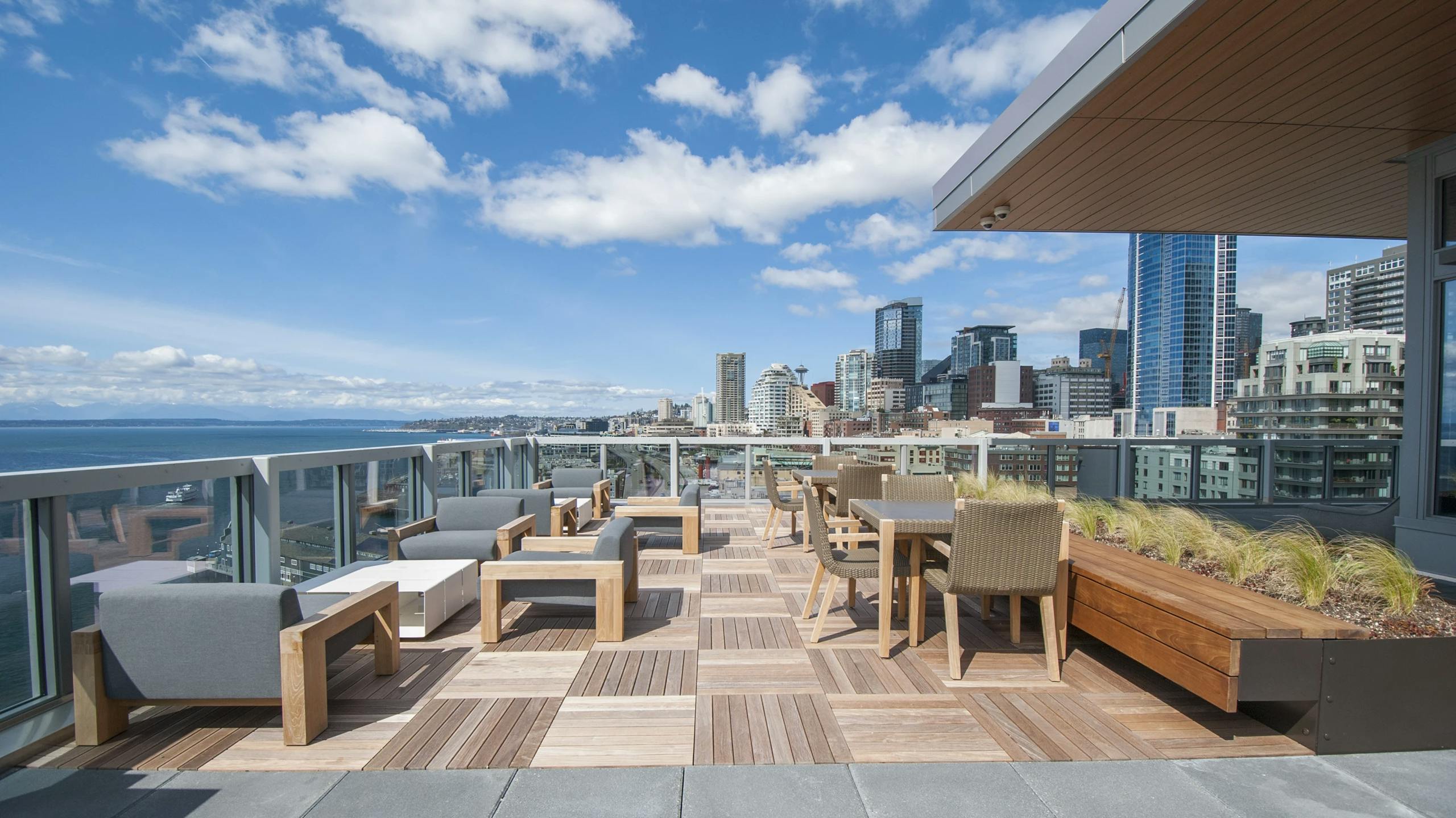 Rooftop deck at AMLI Waterfront apartments with wood furniture, skyline views, bayfront seating, and built-in planters.