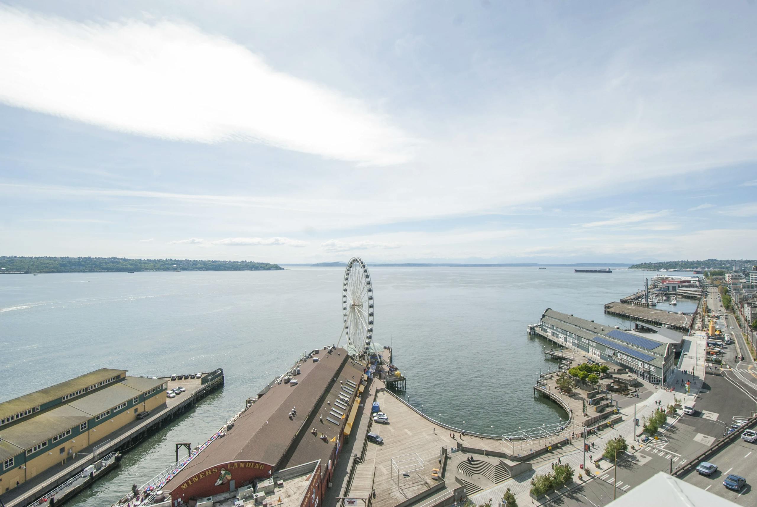 View from AMLI Waterfront apartments overlooking Elliott Bay, Seattle Great Wheel, piers, and tree-lined waterfront street.