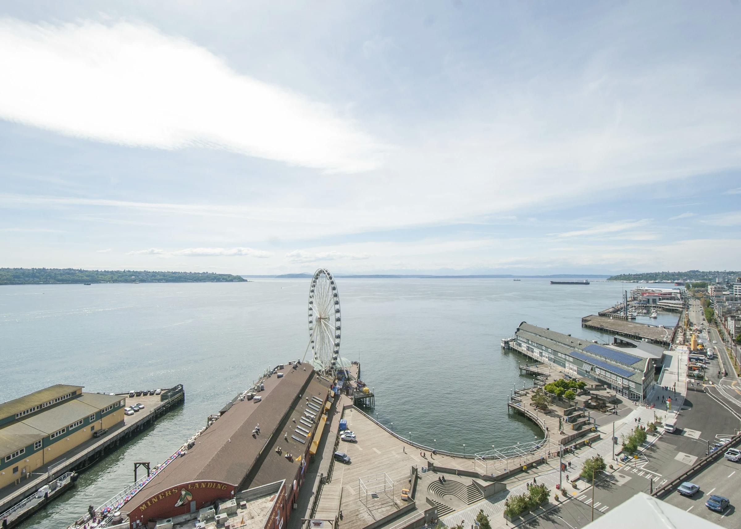 View from AMLI Waterfront apartments overlooking Elliott Bay, Seattle Great Wheel, piers, and tree-lined waterfront street.