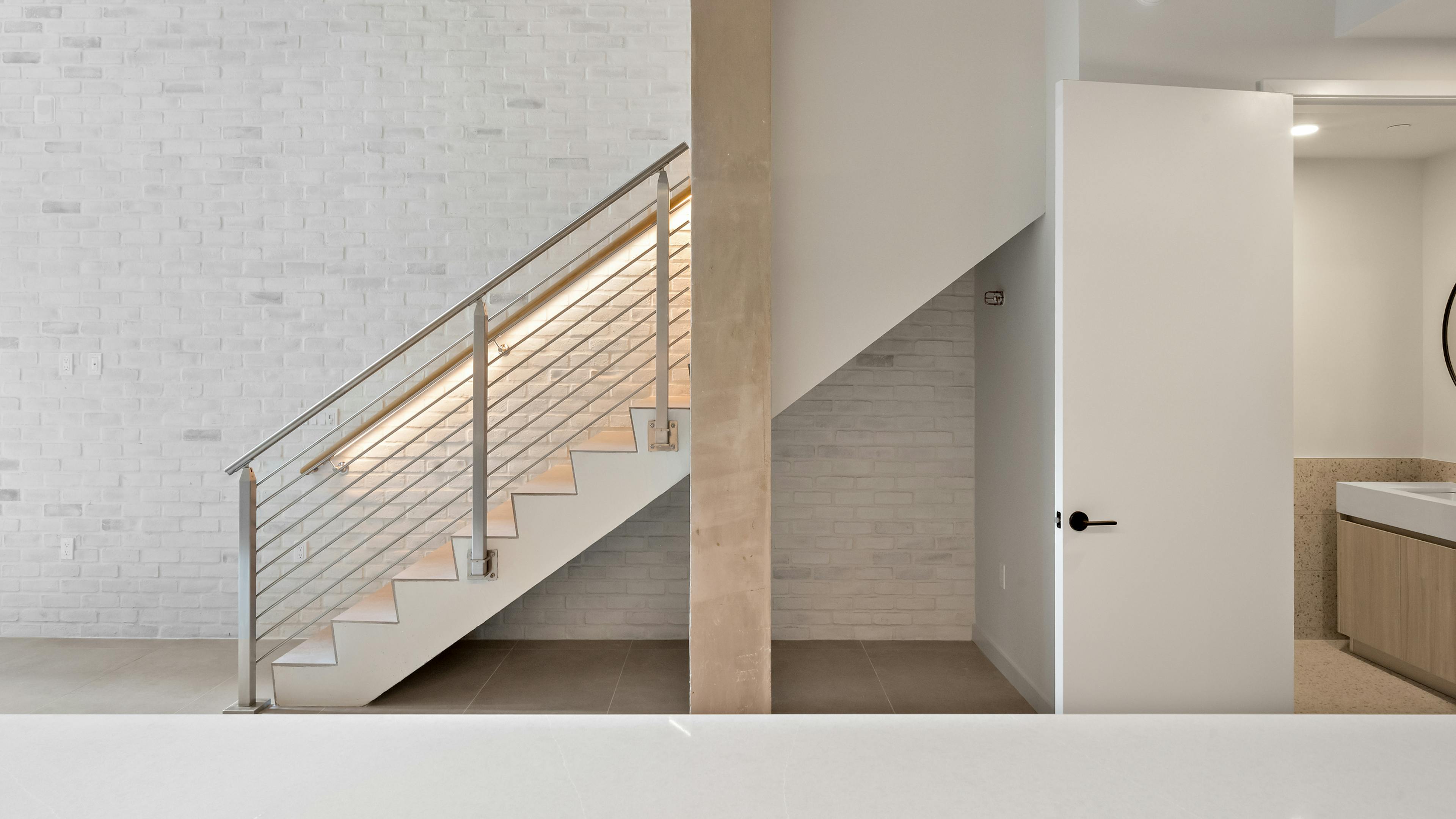 Staircase at AMLI Wynwood with a stone accent wall and recessed lighting.