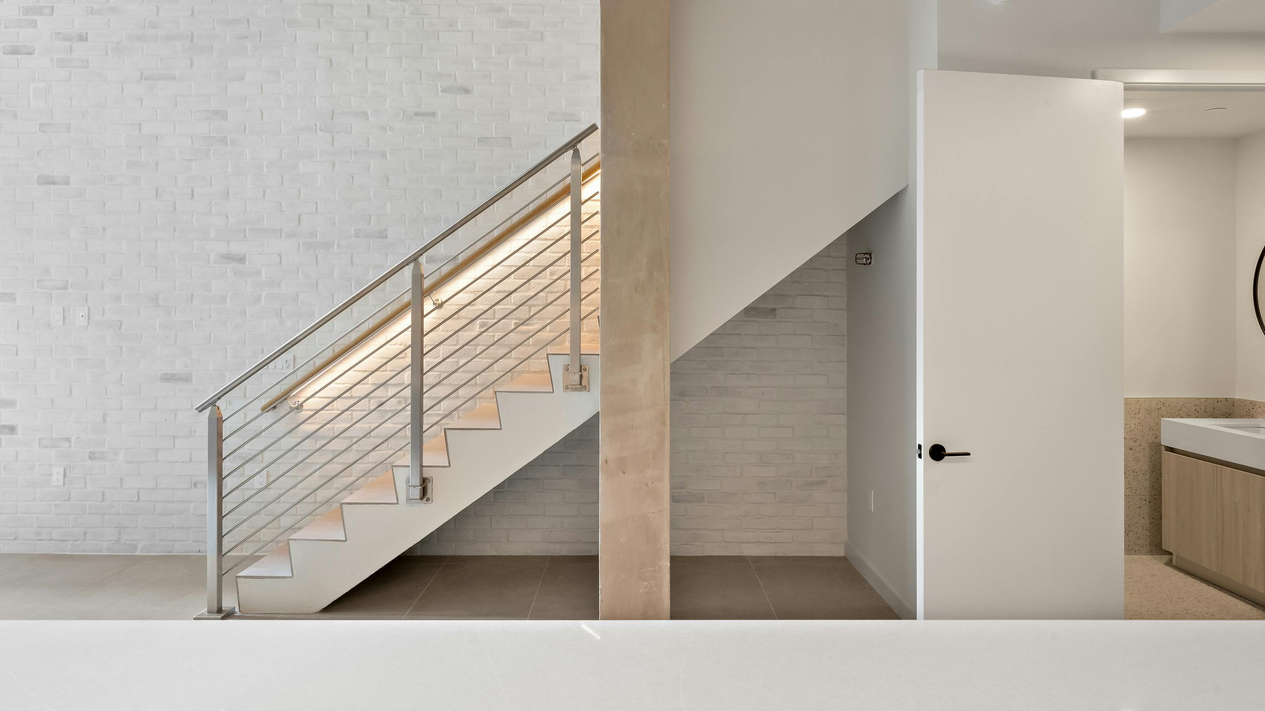 Staircase at AMLI Wynwood with a stone accent wall and recessed lighting.