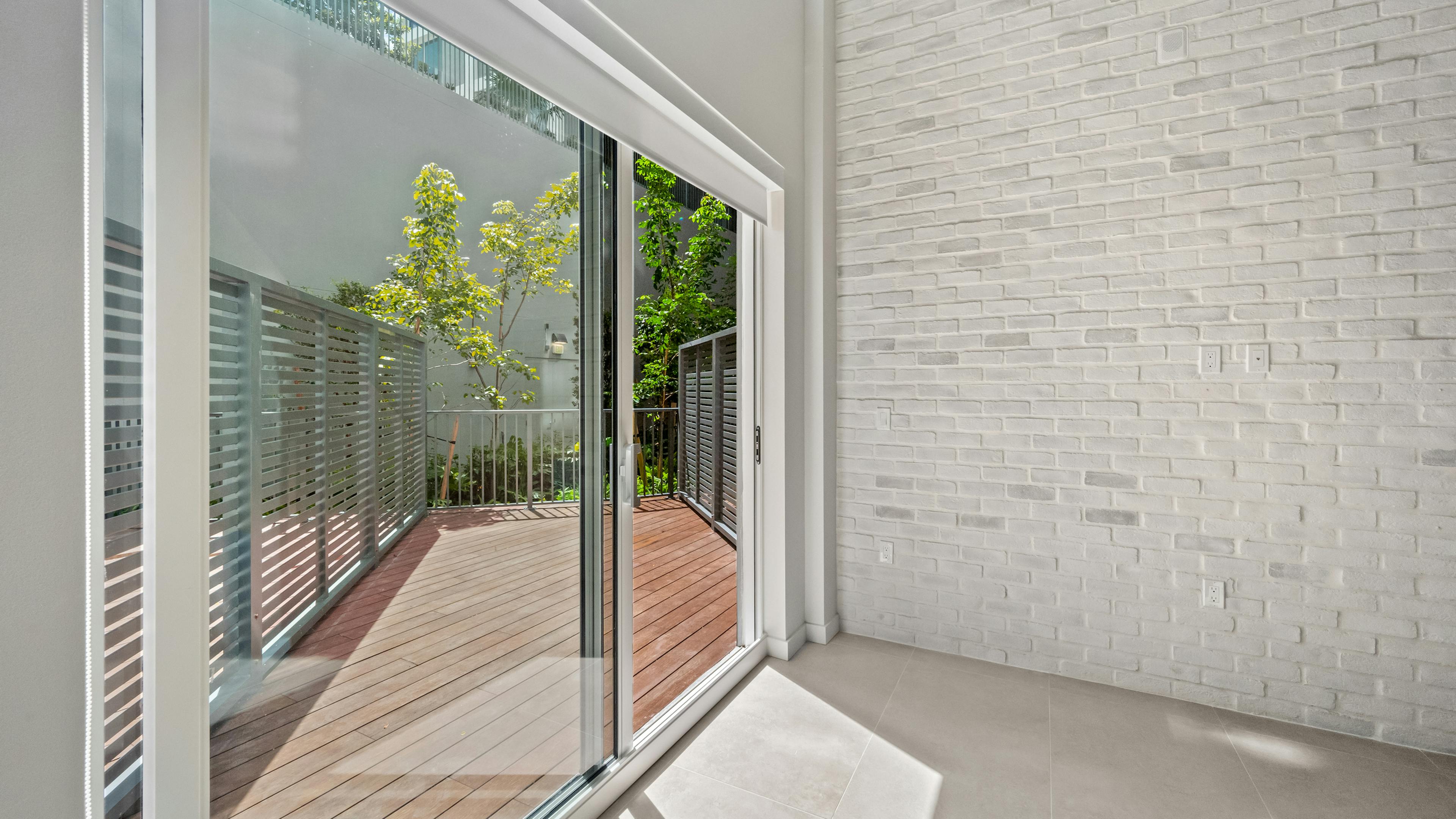 Enclosed patio with a sliding glass door and stone accent wall at AMLI Wynwood.