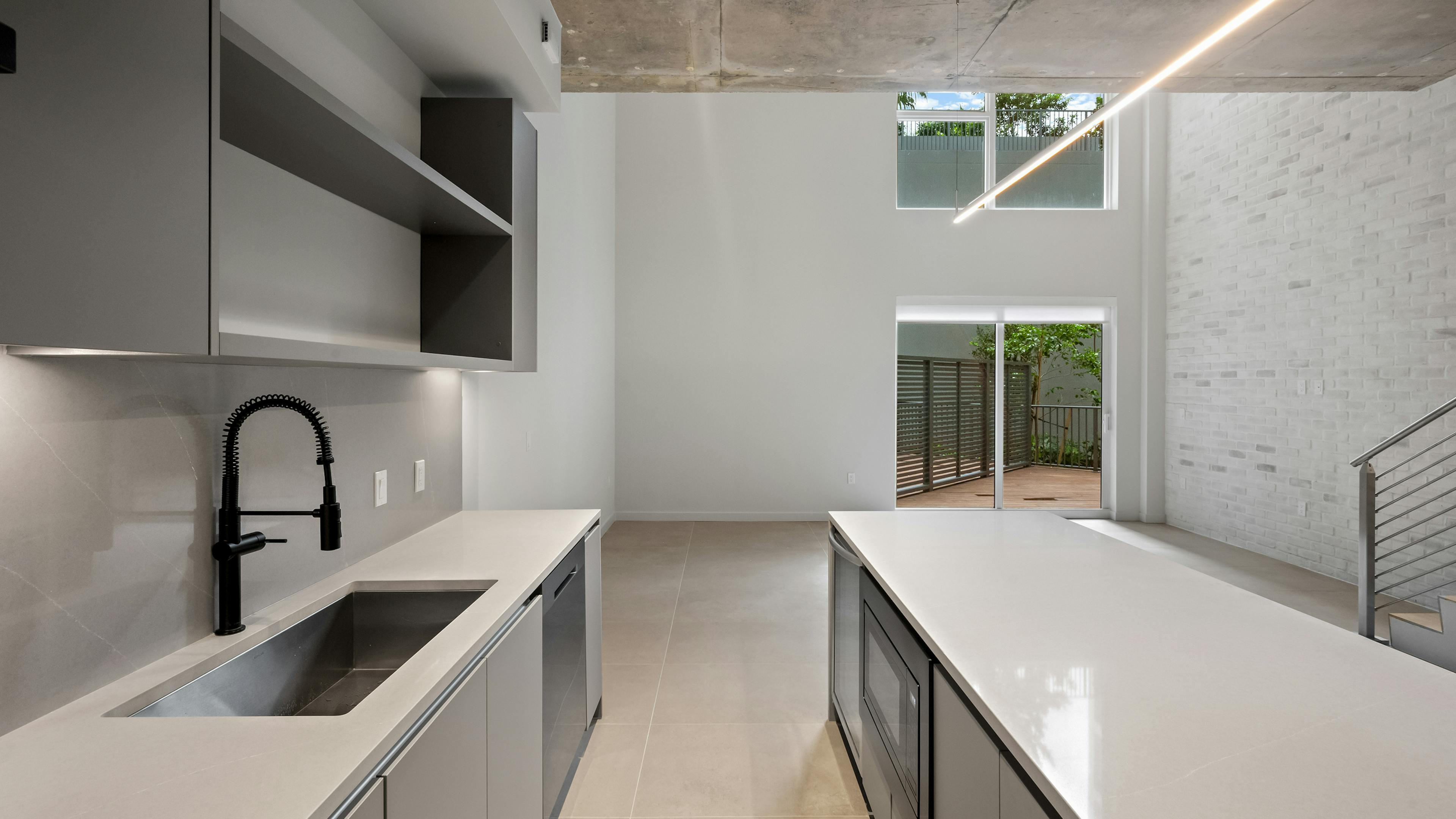 Modern kitchen with grey cabinets and white quartz counters at AMLI Wynwood.