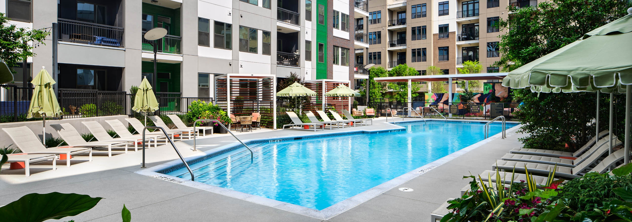 Swimming pool at AMLI Flatiron surrounded by lounge seating and plants.