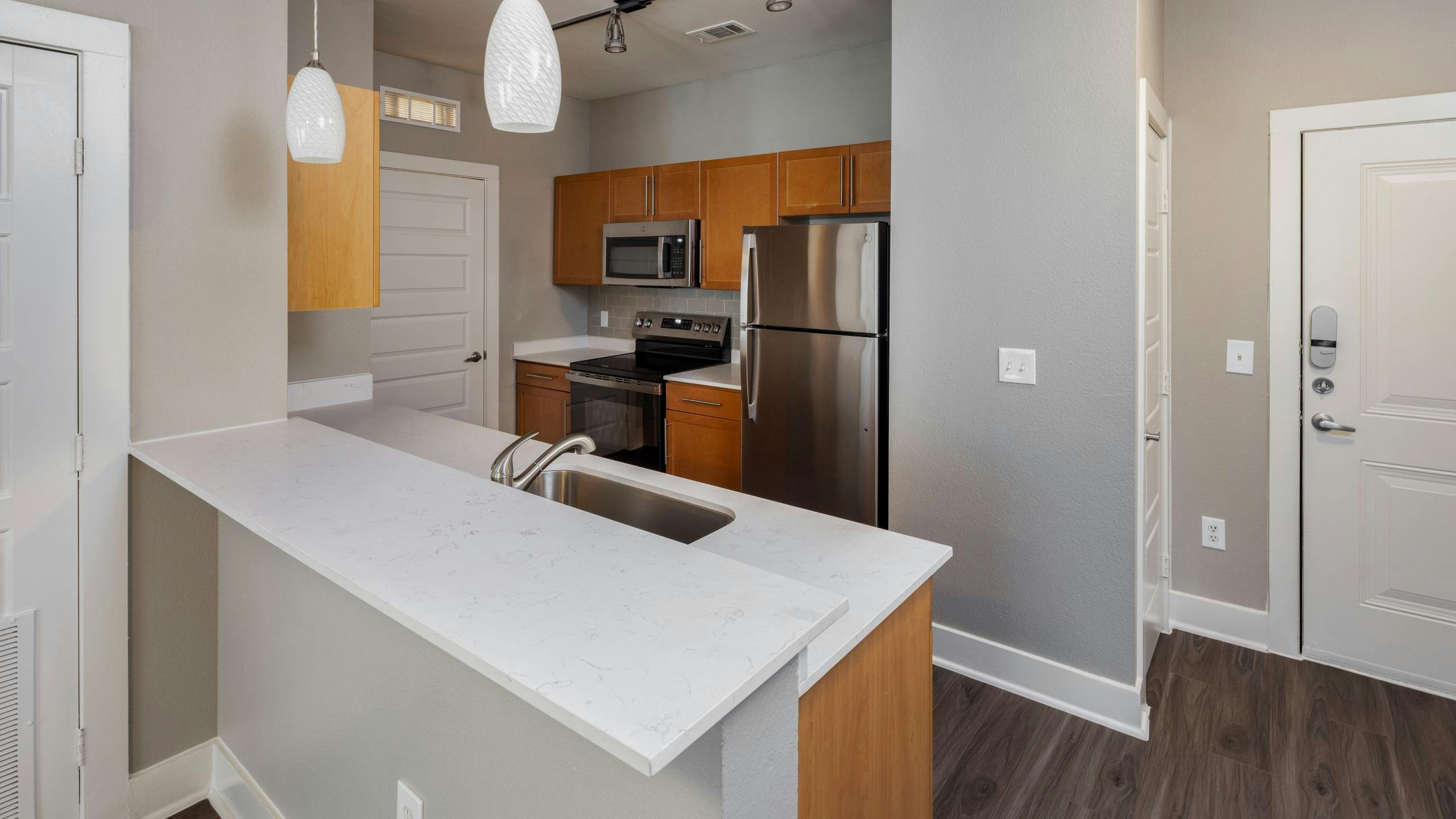 Studio apartment kitchen with light wood cabinets and stainless steel appliances at AMLI South Shore apartments