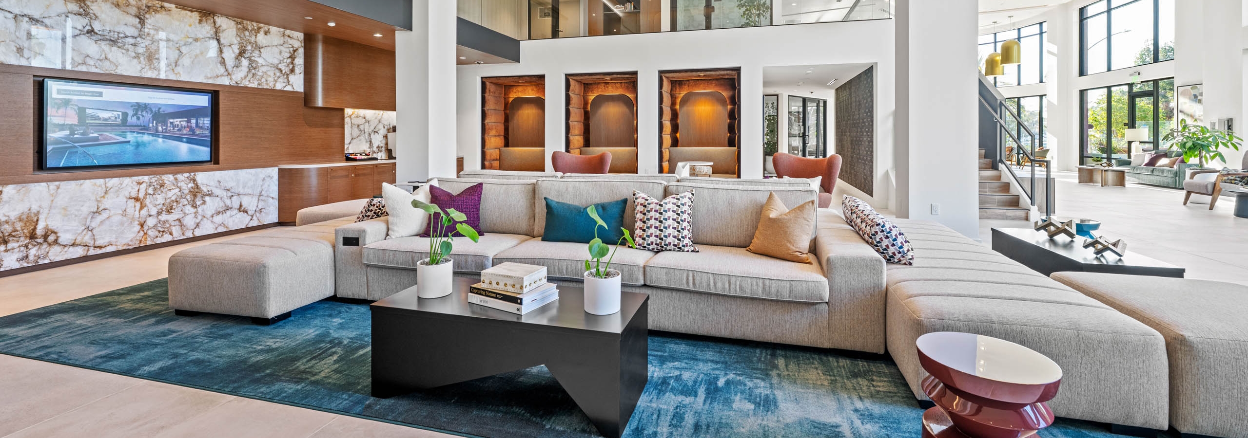 Lobby at AMLI Aero with multiple seating options with a geometric shaped couch and plush pods with bench seating.