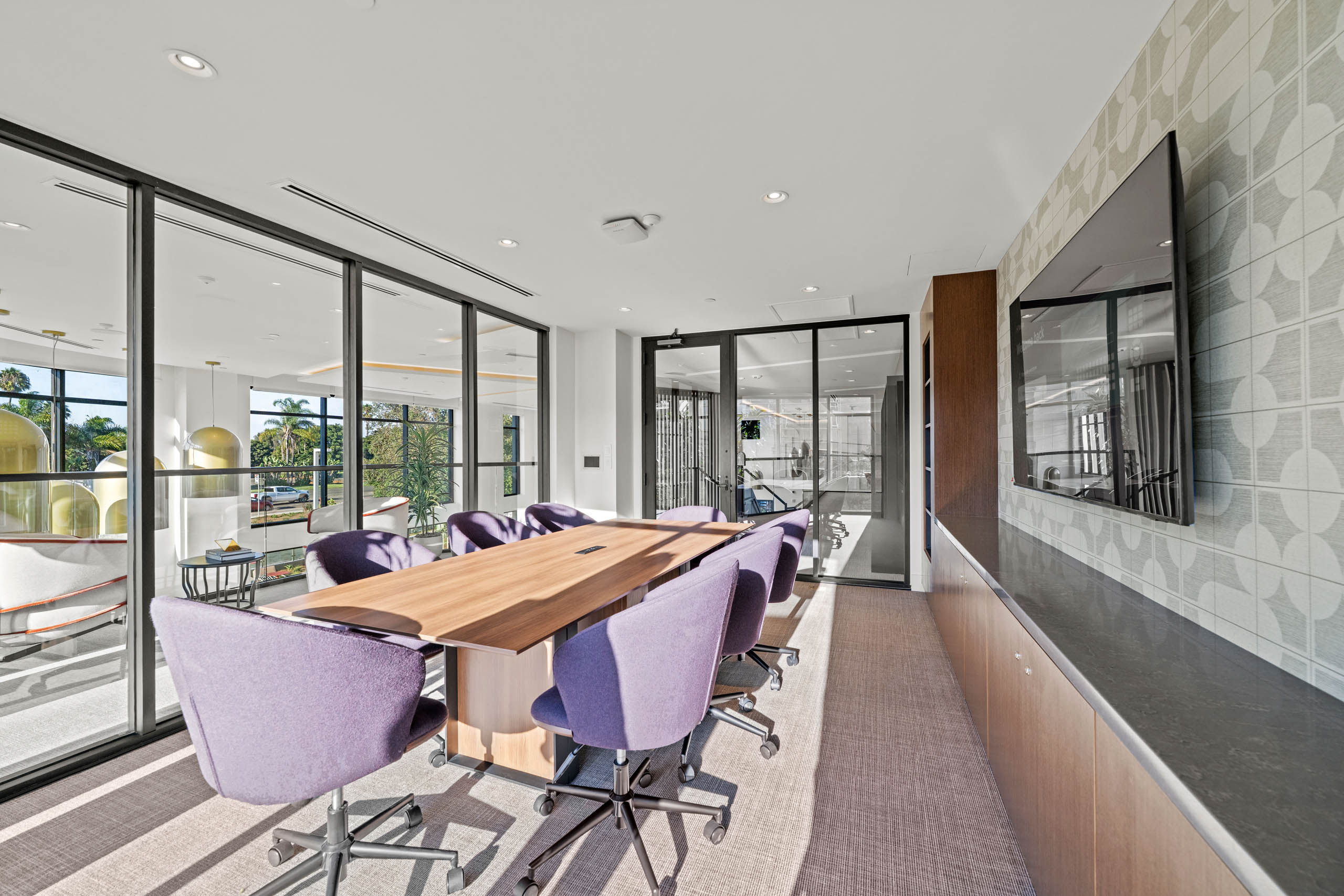 AMLI Aero conference room that seats eight with plush chairs surrounded by glass and natural light from every direction.