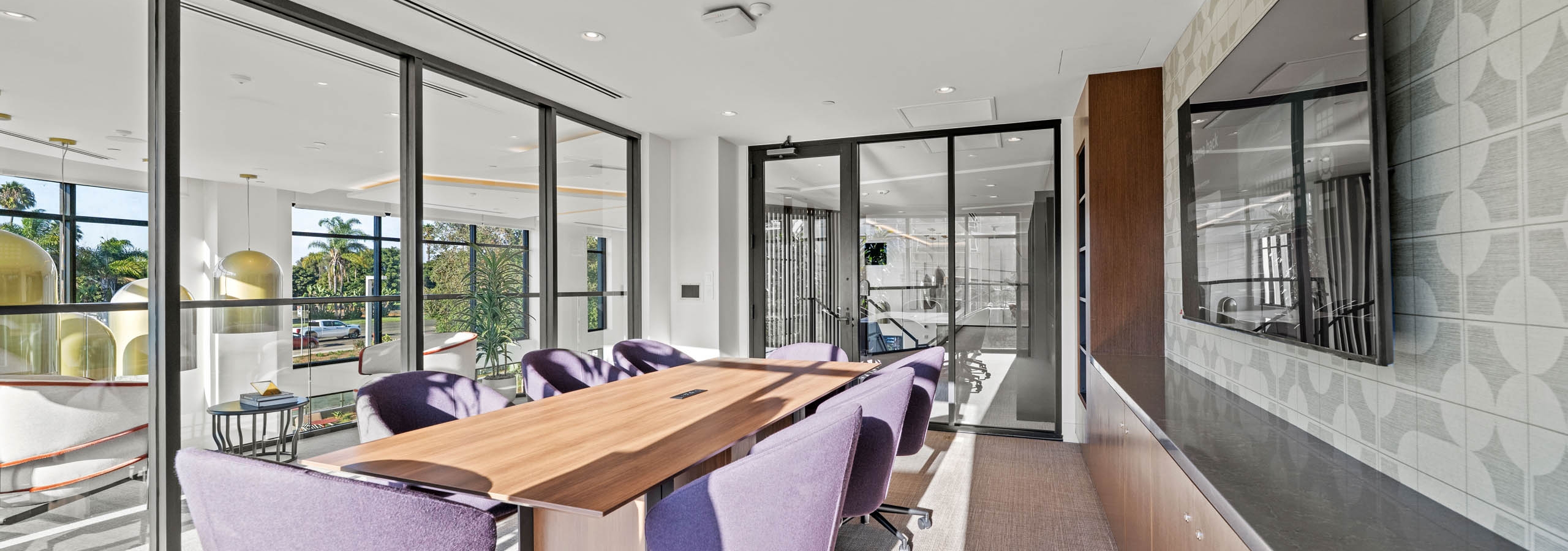 AMLI Aero conference room that seats eight with plush chairs surrounded by glass and natural light from every direction.