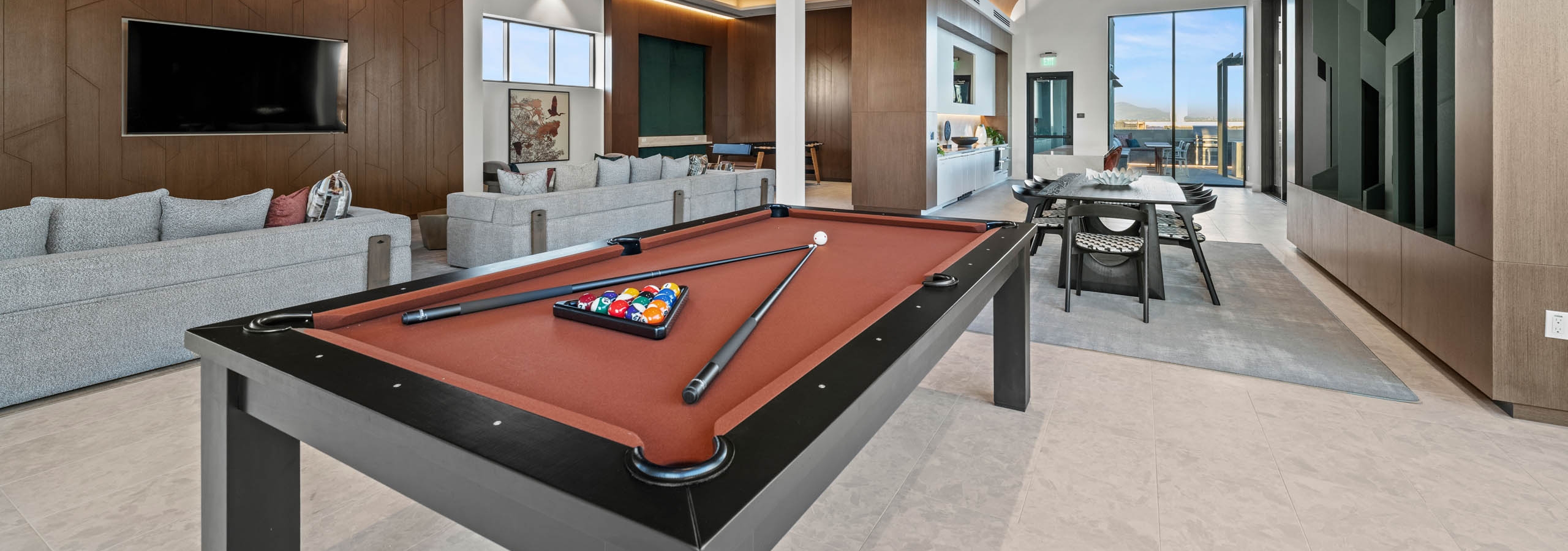 AMLI Aero clubroom with lightly colored walls and flooring and several windows with a dark textured wall and modern pool table.