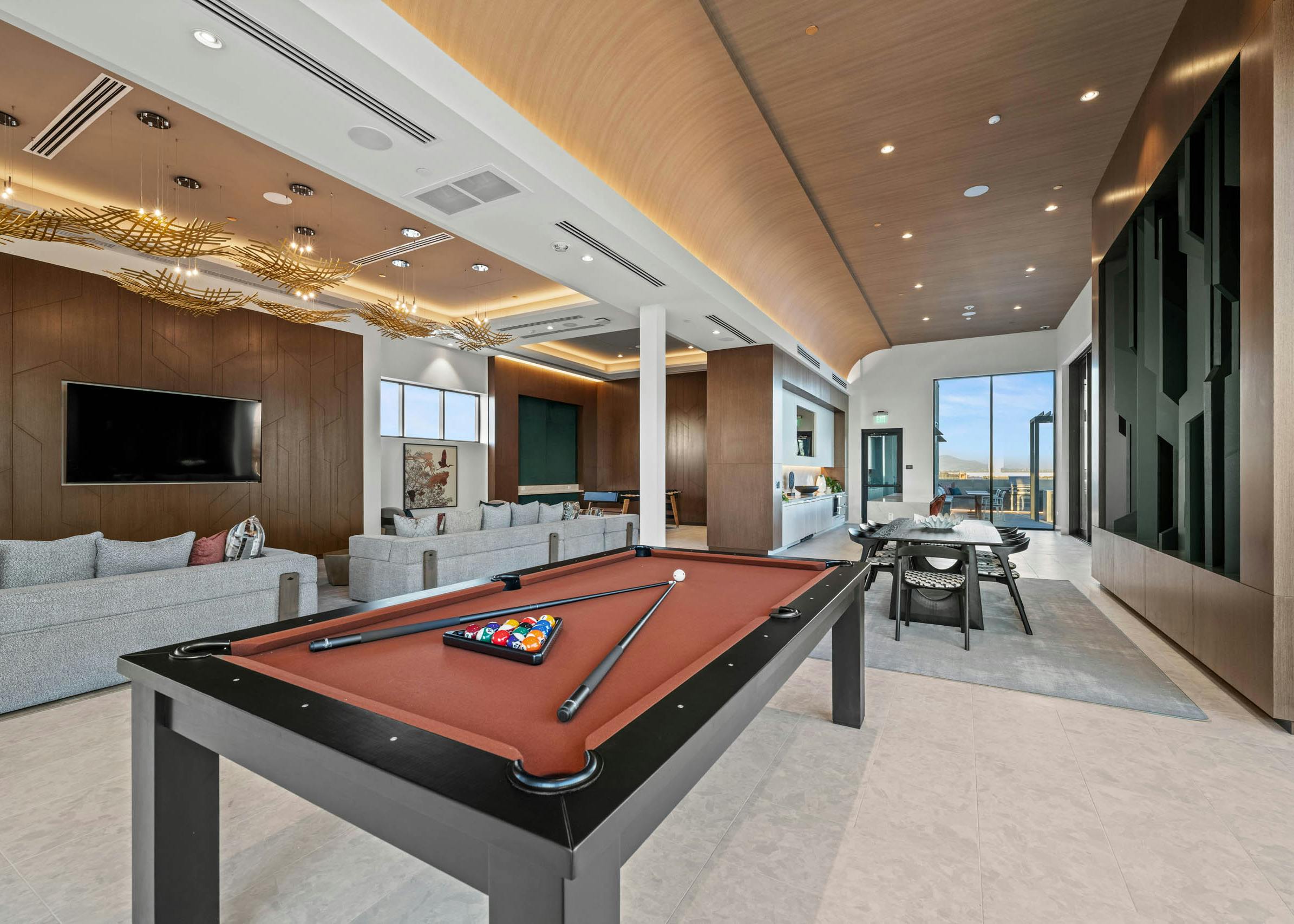 AMLI Aero clubroom with lightly colored walls and flooring and several windows with a dark textured wall and modern pool table.