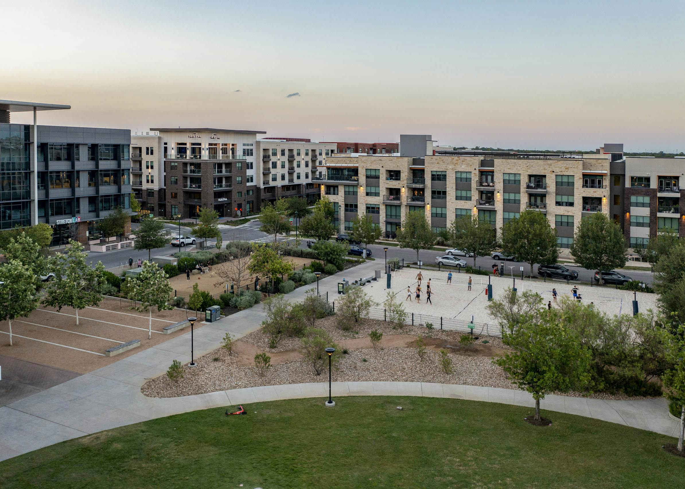 Aerial view of AMLI North Park apartments at sunset overlooking Elizabeth Mary Branch Park with a dog park and volleyball court