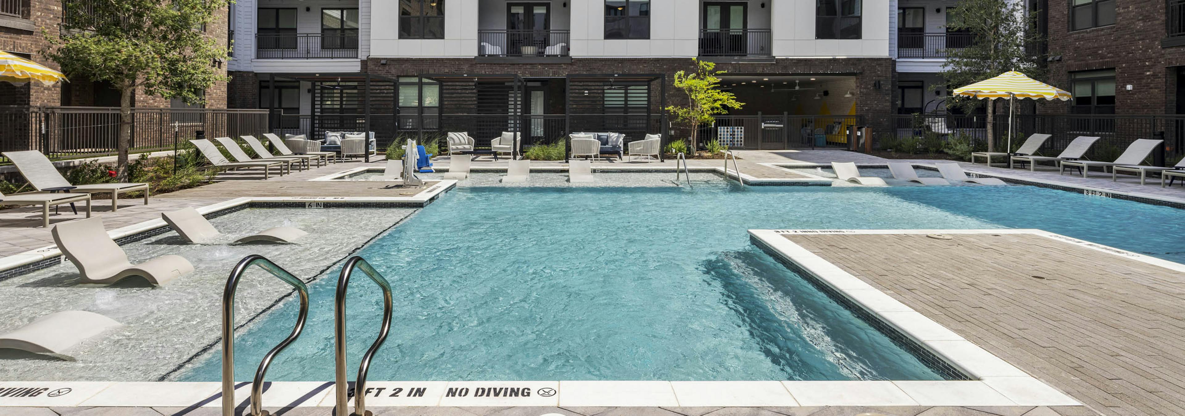 Swimming pool in the main courtyard of AMLI North Park apartments featuring lounge chairs umbrellas and thoughtful landscaping