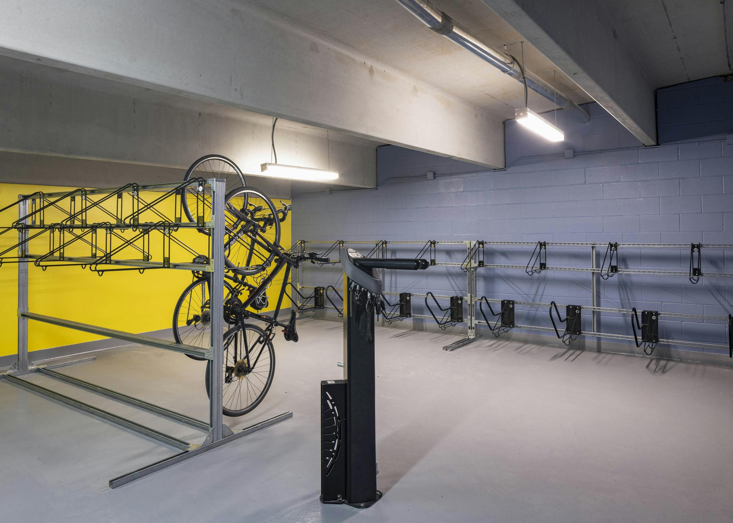Bike room at AMLI North Park with yellow and blue walls metal racks on both sides and several bikes hanging vertically