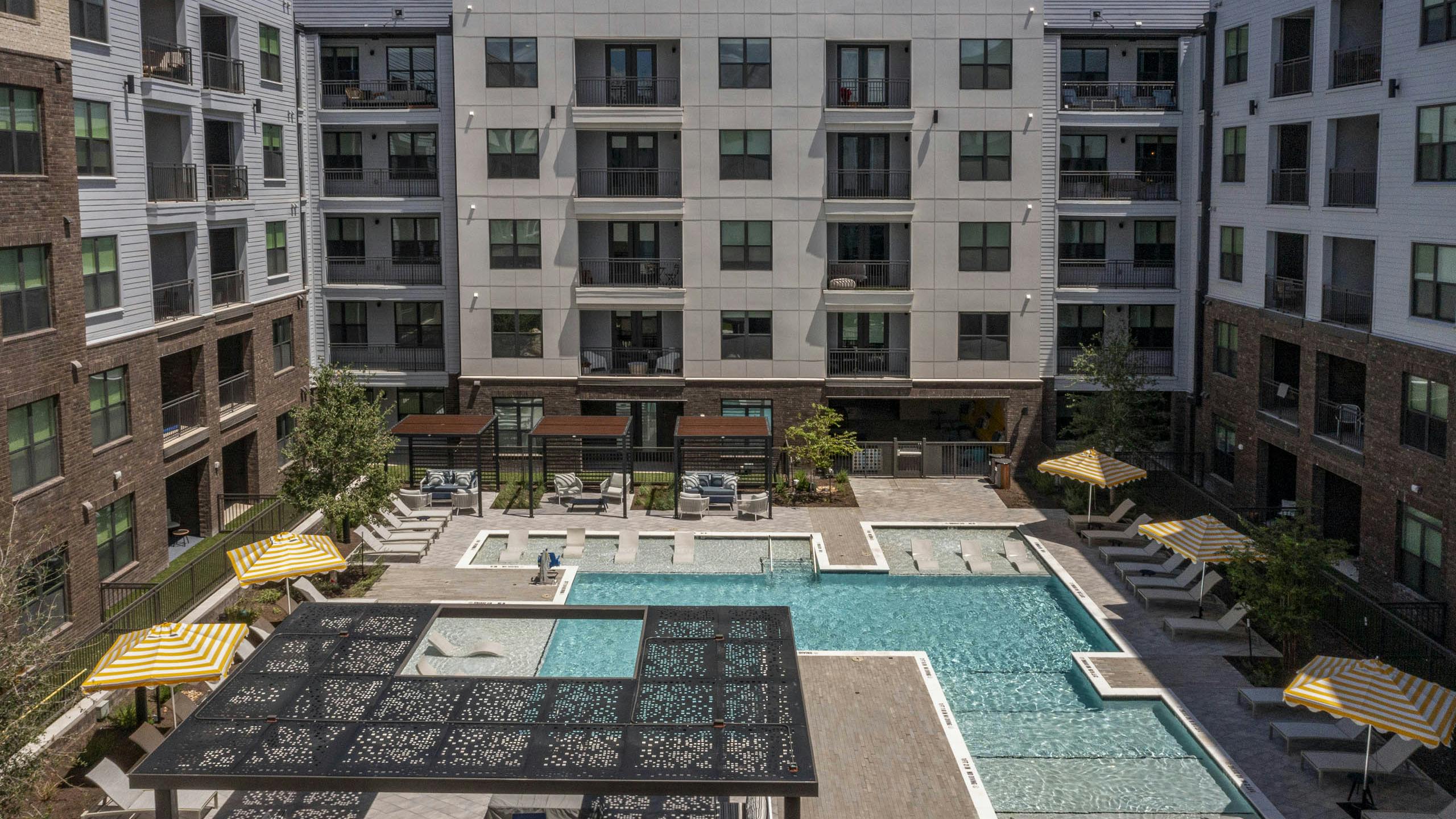 Courtyard at AMLI North Park with swimming pool lounge chairs umbrellas shaded seating and apartment buildings with balconies