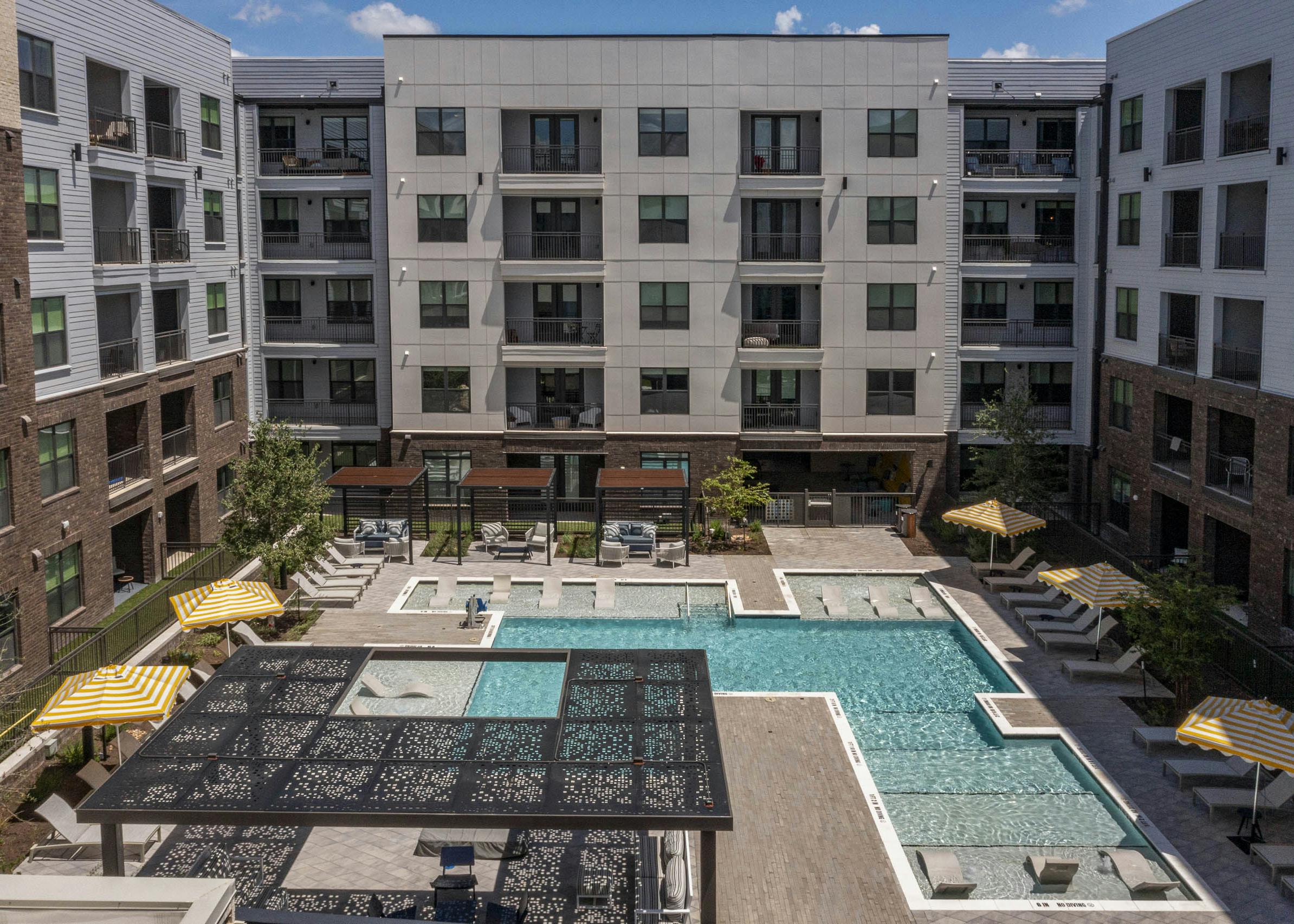 Courtyard at AMLI North Park with swimming pool lounge chairs umbrellas shaded seating and apartment buildings with balconies