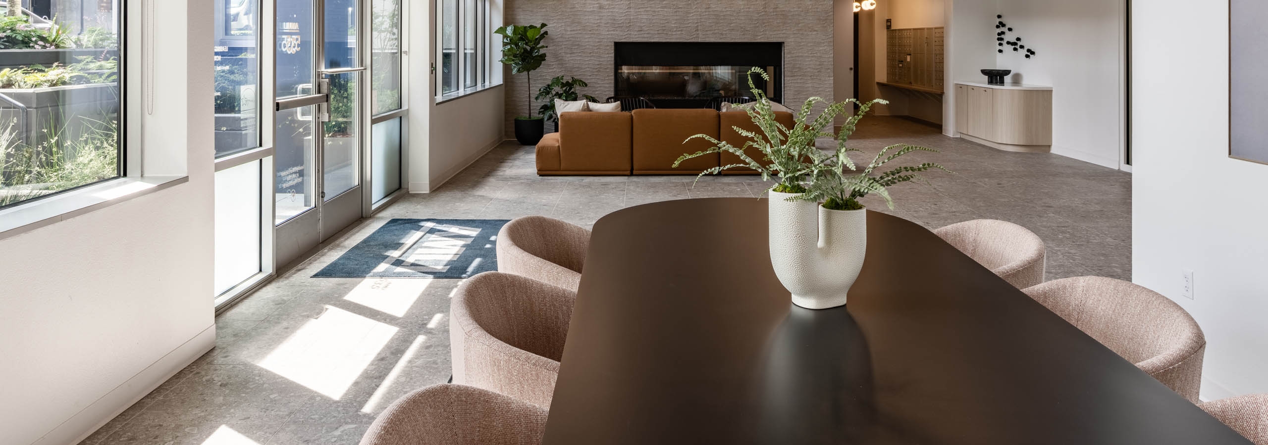 Lobby view at AMLI 535 apartments with pendant lighting, tall windows, fireplace, and soft seating near mail area and entry.