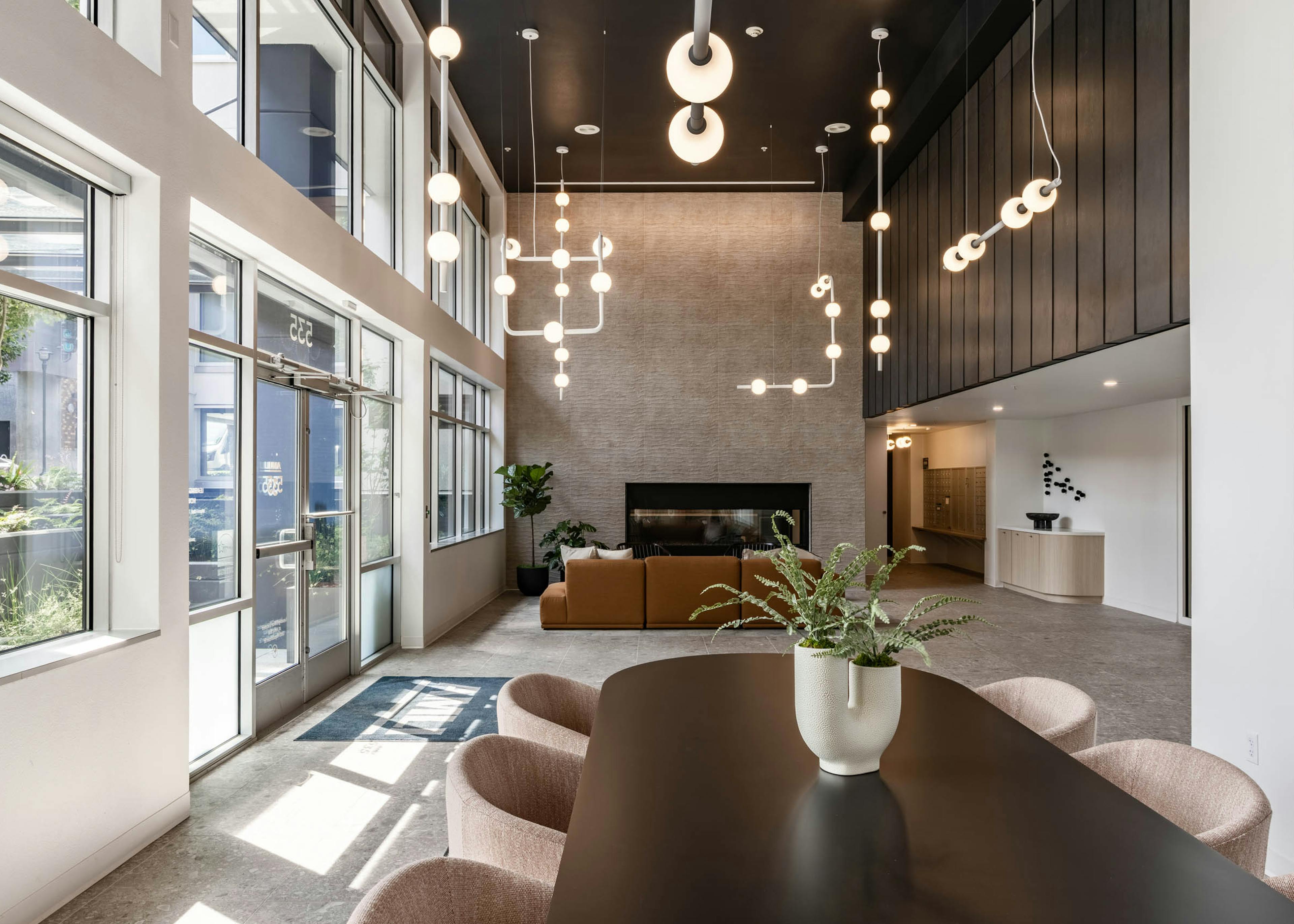 Lobby view at AMLI 535 apartments with pendant lighting, tall windows, fireplace, and soft seating near mail area and entry.