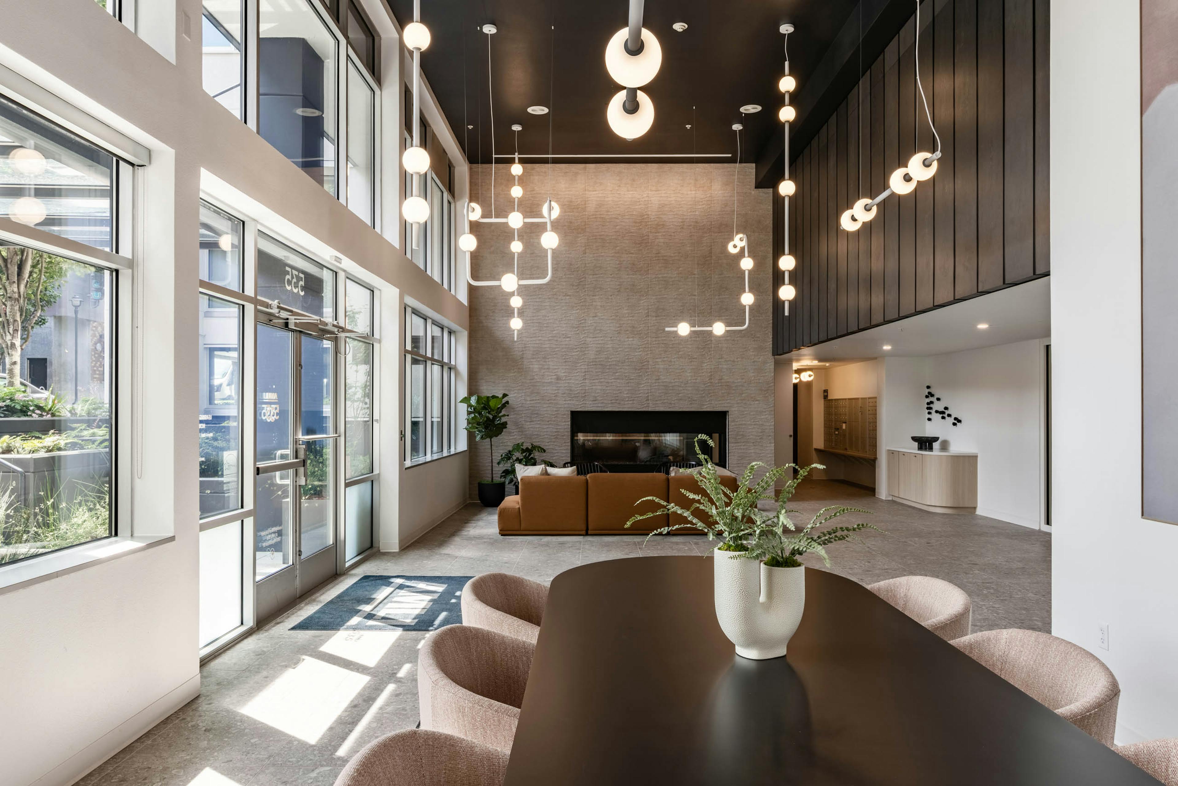Lobby view at AMLI 535 apartments with pendant lighting, tall windows, fireplace, and soft seating near mail area and entry.