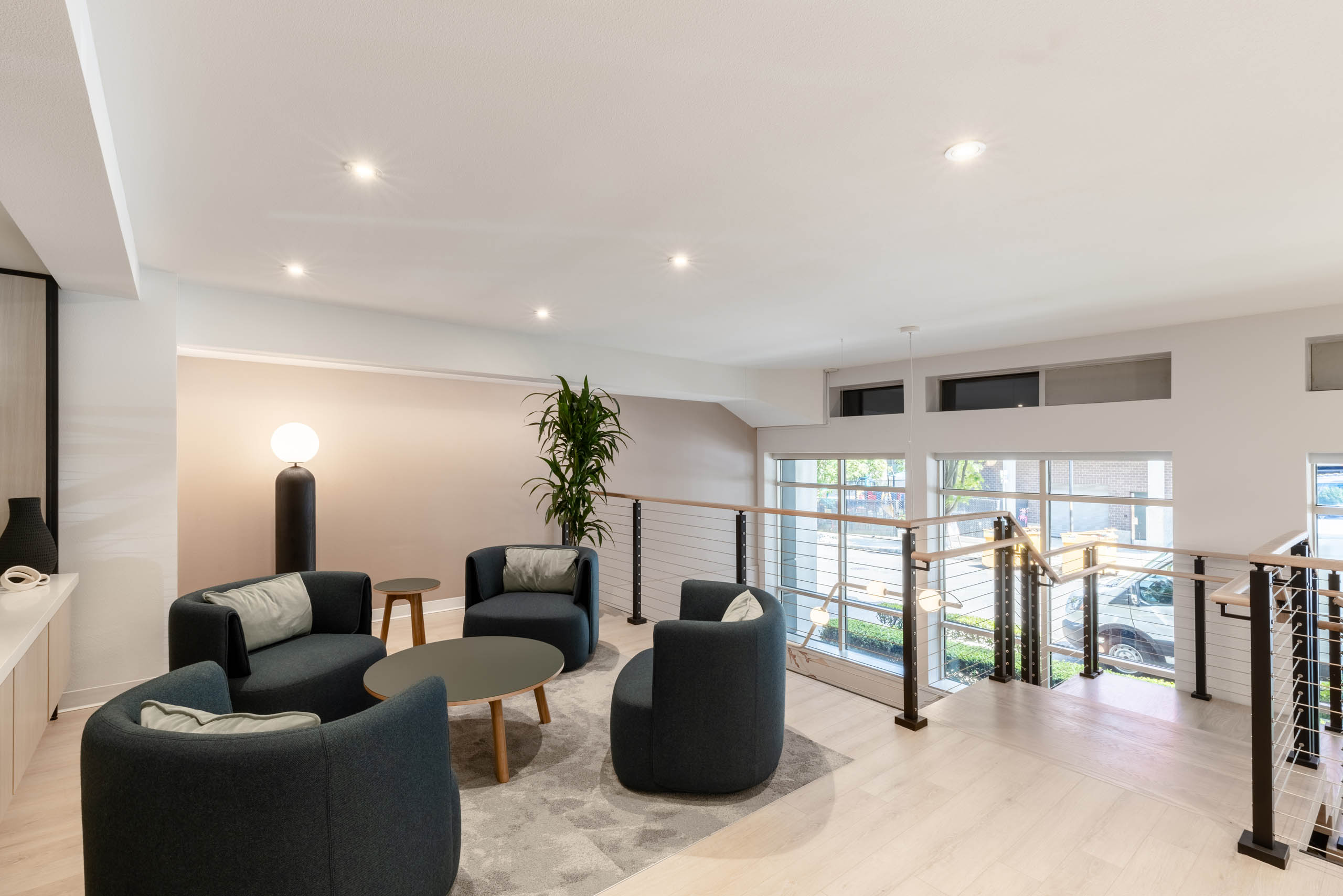 Upper-level seating area at AMLI 535 apartments with four modern chairs, round tables, large windows, and view of the street below.