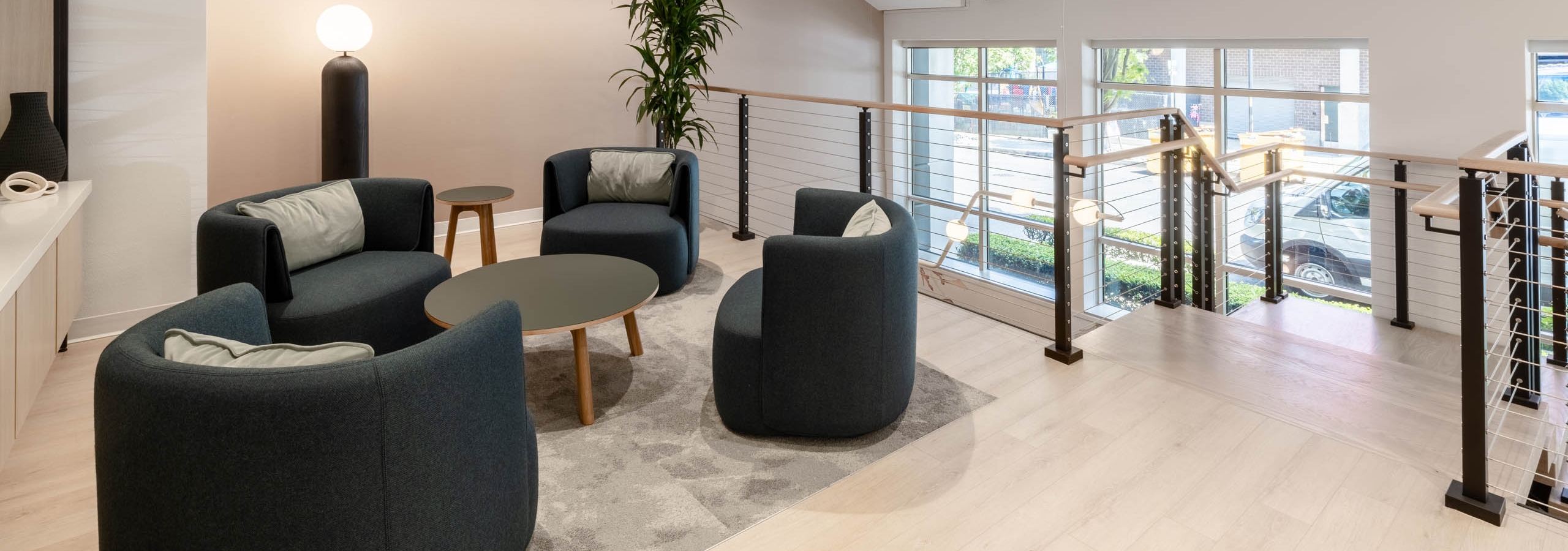 Upper-level seating area at AMLI 535 apartments with four modern chairs, round tables, large windows, and view of the street below.