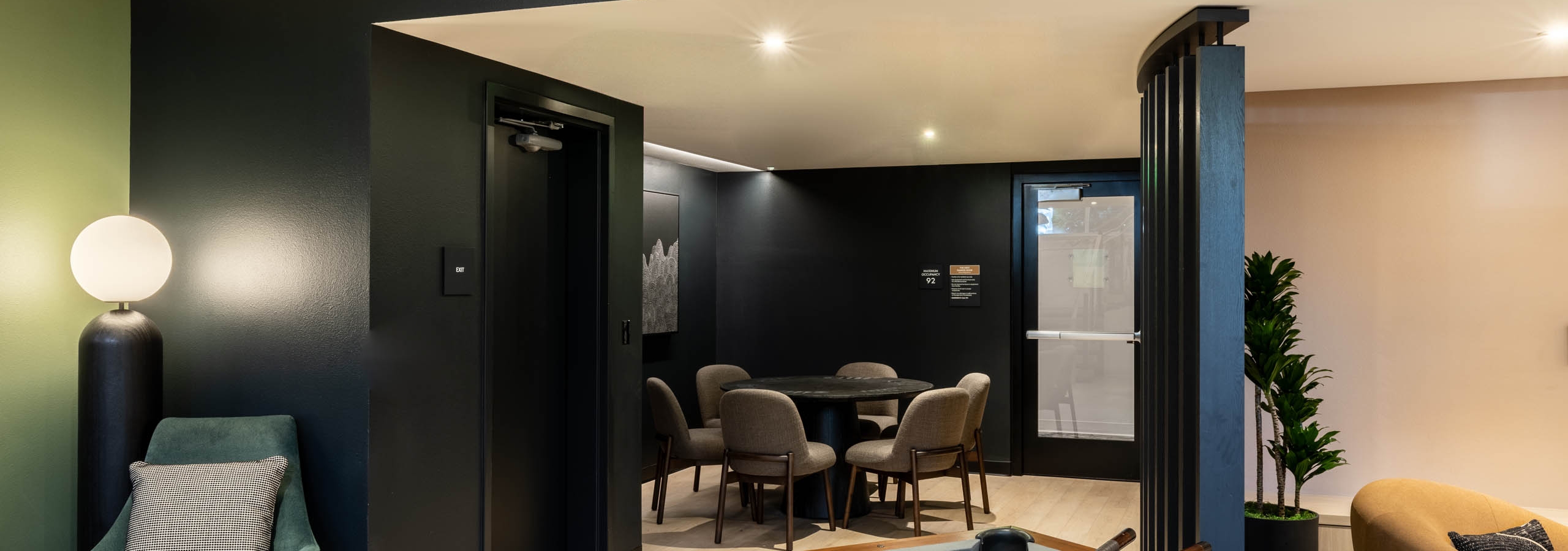 View of AMLI 535 apartments gaming nook with pool table, cue sticks, plush green chair, and poker table surrounded by black walls.