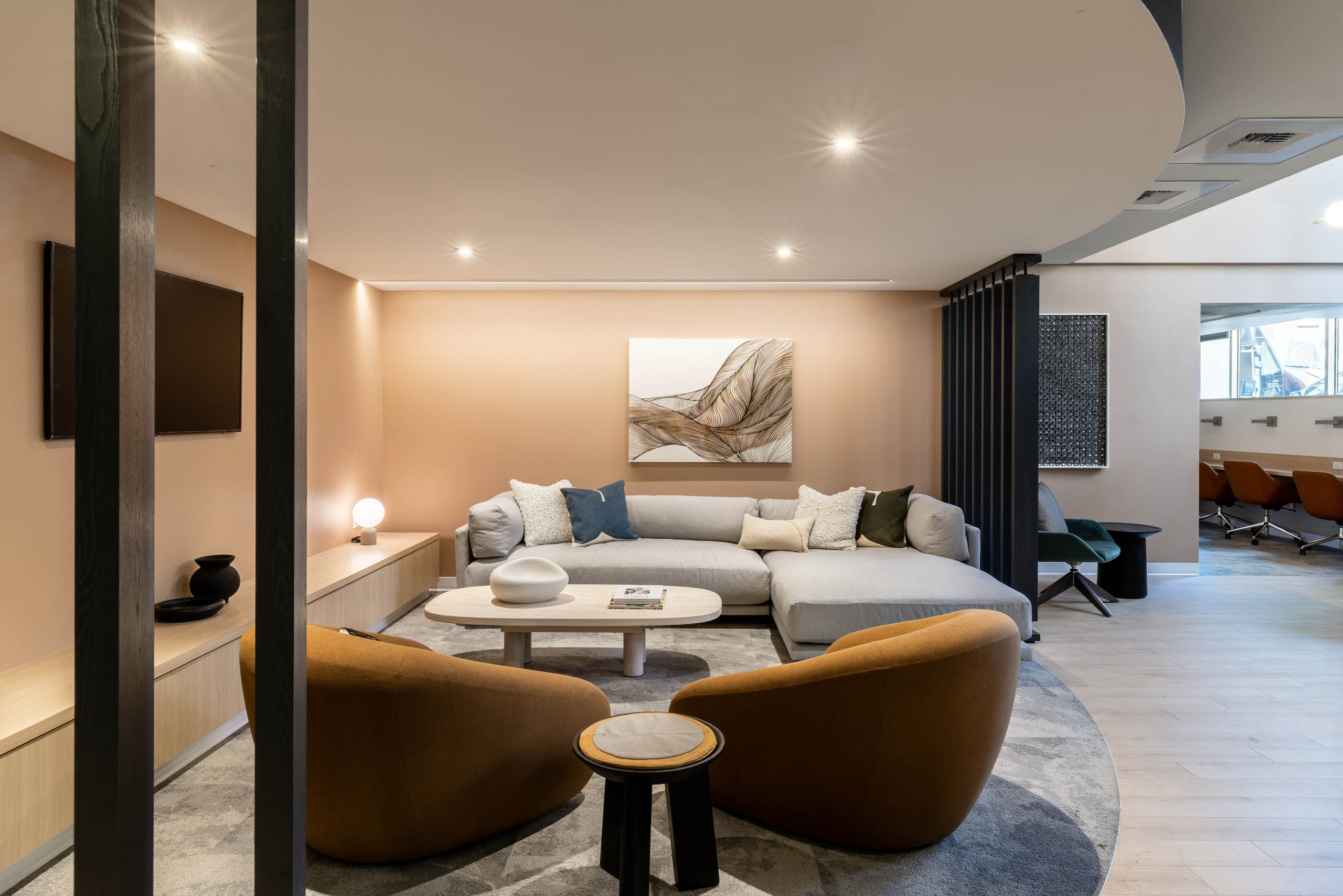 Cozy corner lounge at AMLI 535 apartments with plush light gray sectional, tan coffee table, brown accent chairs, and wall-mounted TV.