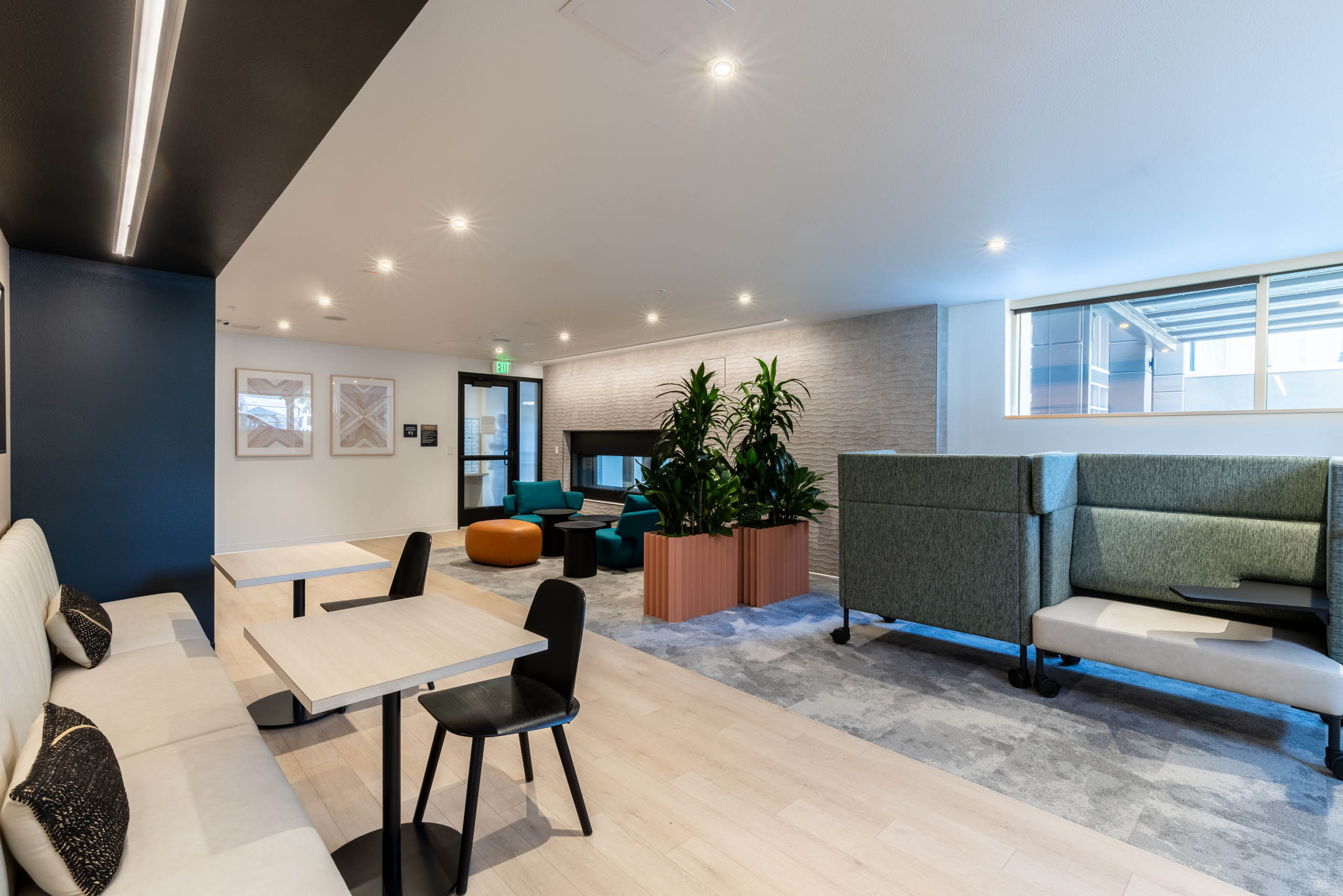 Community lounge at AMLI 535 apartments with booth and table seating, lounge chairs, potted plants, and a contemporary fireplace.
