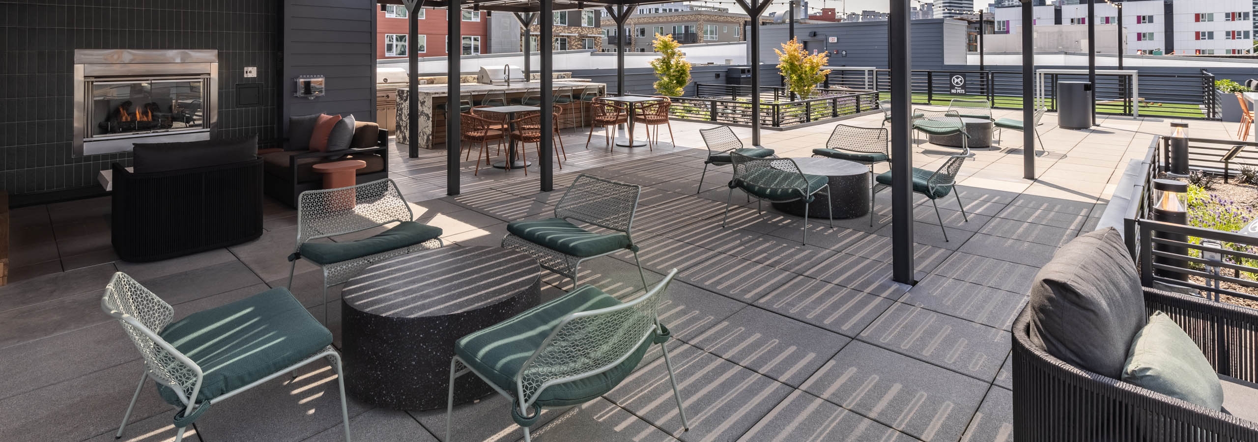 Covered rooftop deck at AMLI 535 apartments with fireplace, lounge seating, and city views framed by open black pergola structure.