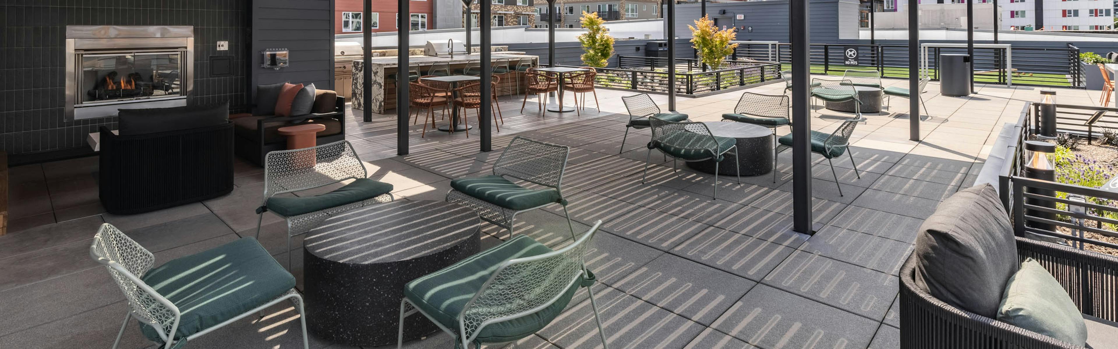 Covered rooftop deck at AMLI 535 apartments with fireplace, lounge seating, and city views framed by open black pergola structure.