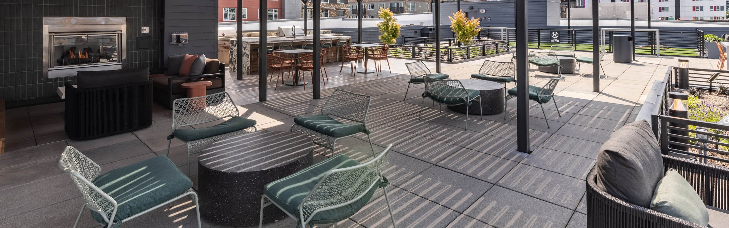 Covered rooftop deck at AMLI 535 apartments with fireplace, lounge seating, and city views framed by open black pergola structure.