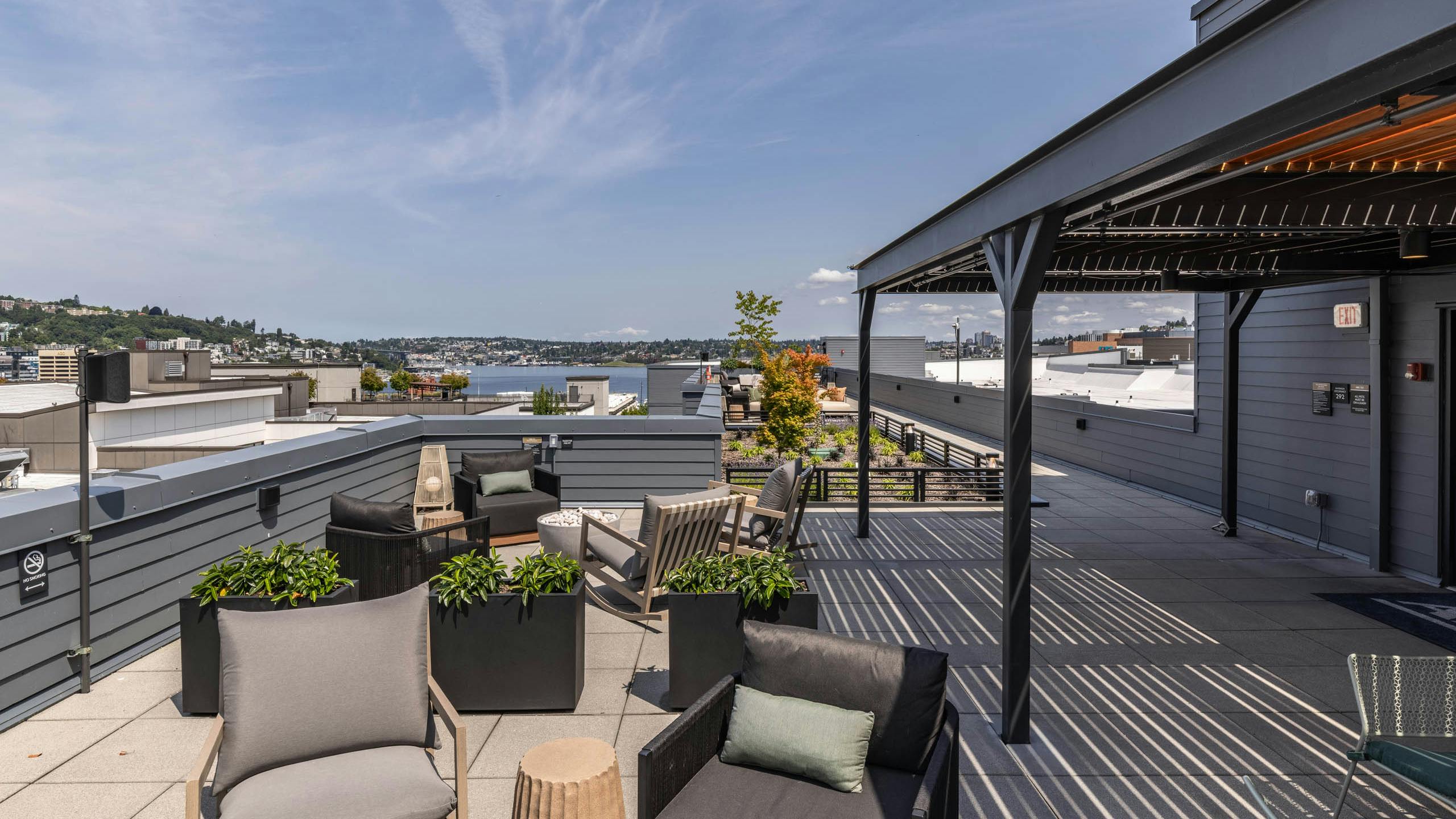 Rooftop seating at AMLI 535 apartments with planters, gray chairs, and sweeping views of Lake Union and the surrounding hills.