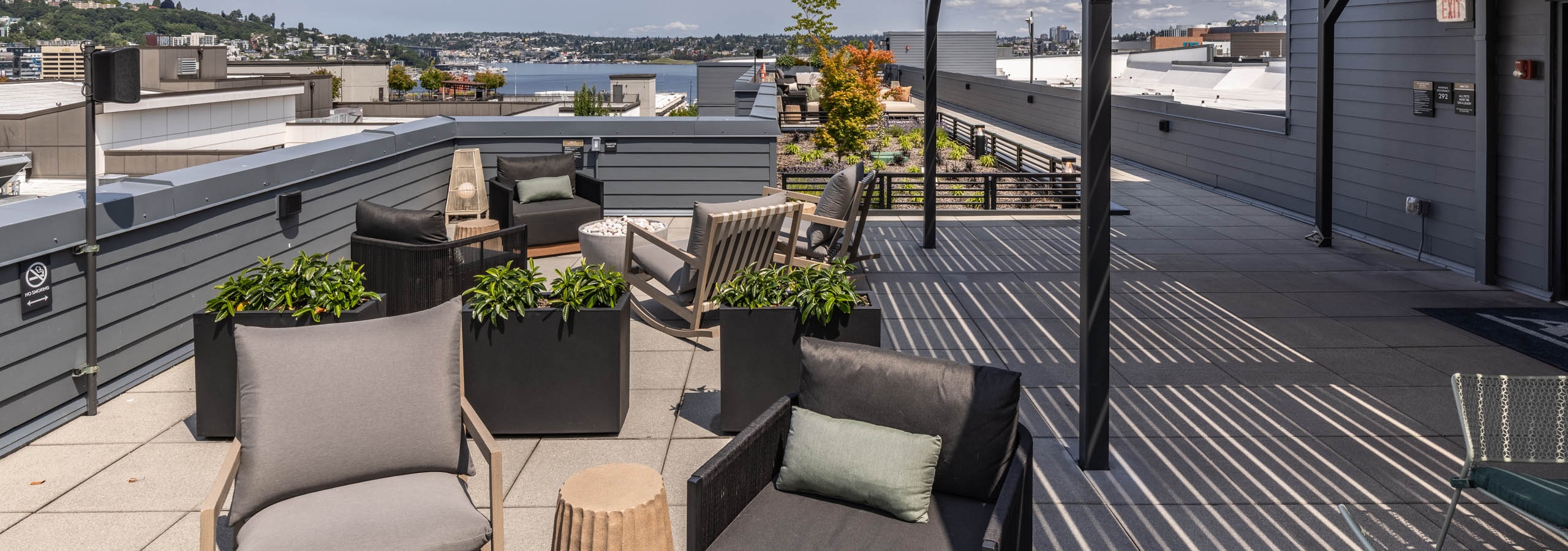 Rooftop seating at AMLI 535 apartments with planters, gray chairs, and sweeping views of Lake Union and the surrounding hills.