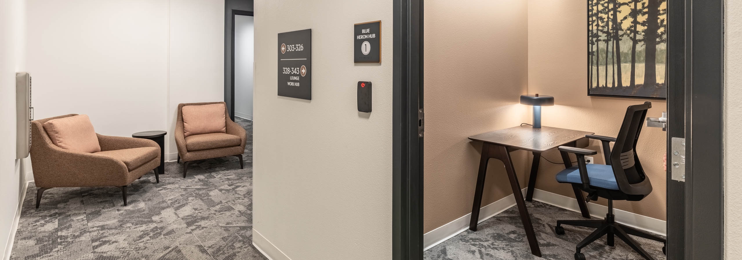 Private work hub at AMLI 535 apartments with desk, task chair, accent lighting, wall art of tall trees and hallway seating
