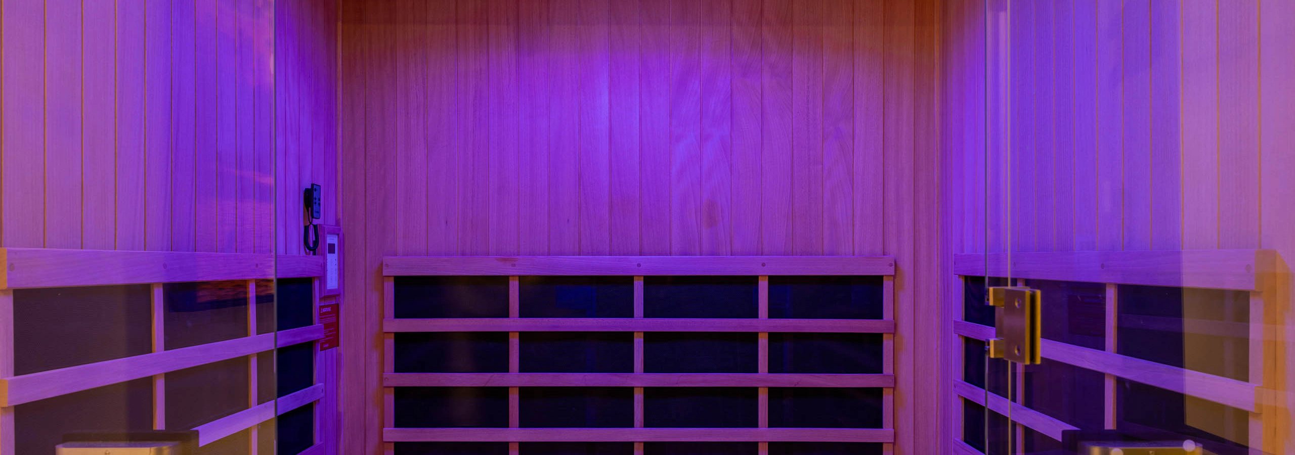 Infrared sauna room at AMLI 535 apartments featuring natural wood interior, bench seating, and soft purple mood lighting.