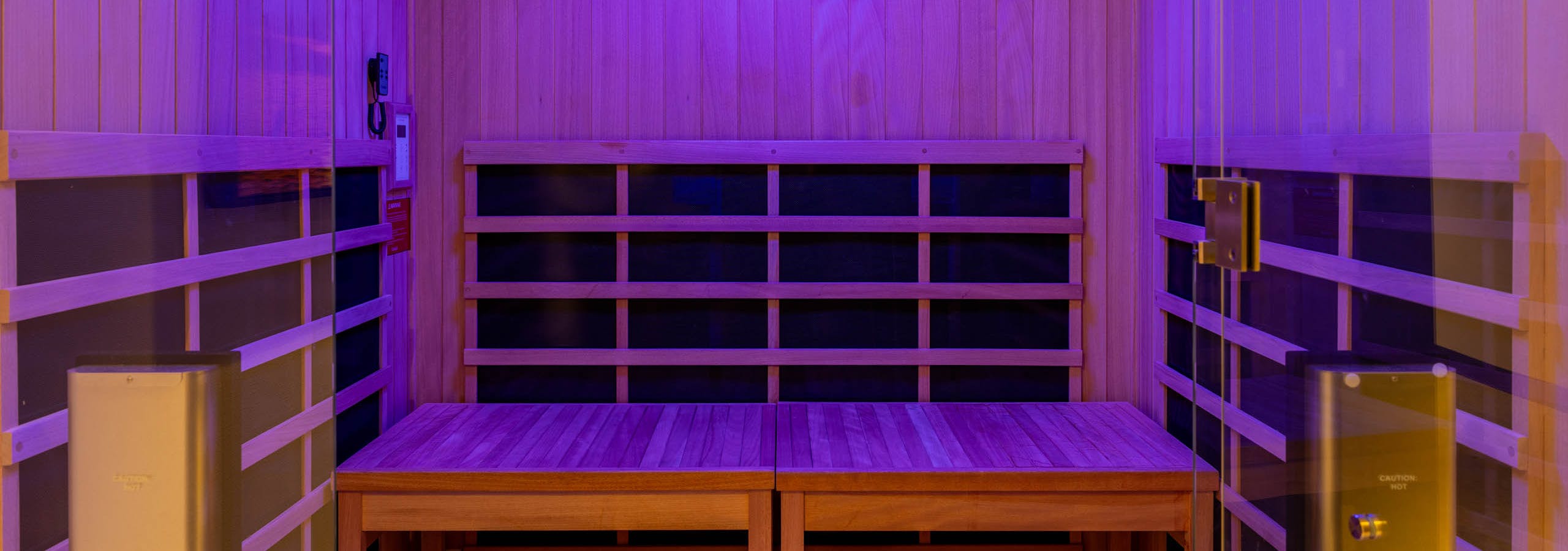 Infrared sauna room at AMLI 535 apartments featuring natural wood interior, bench seating, and soft purple mood lighting.