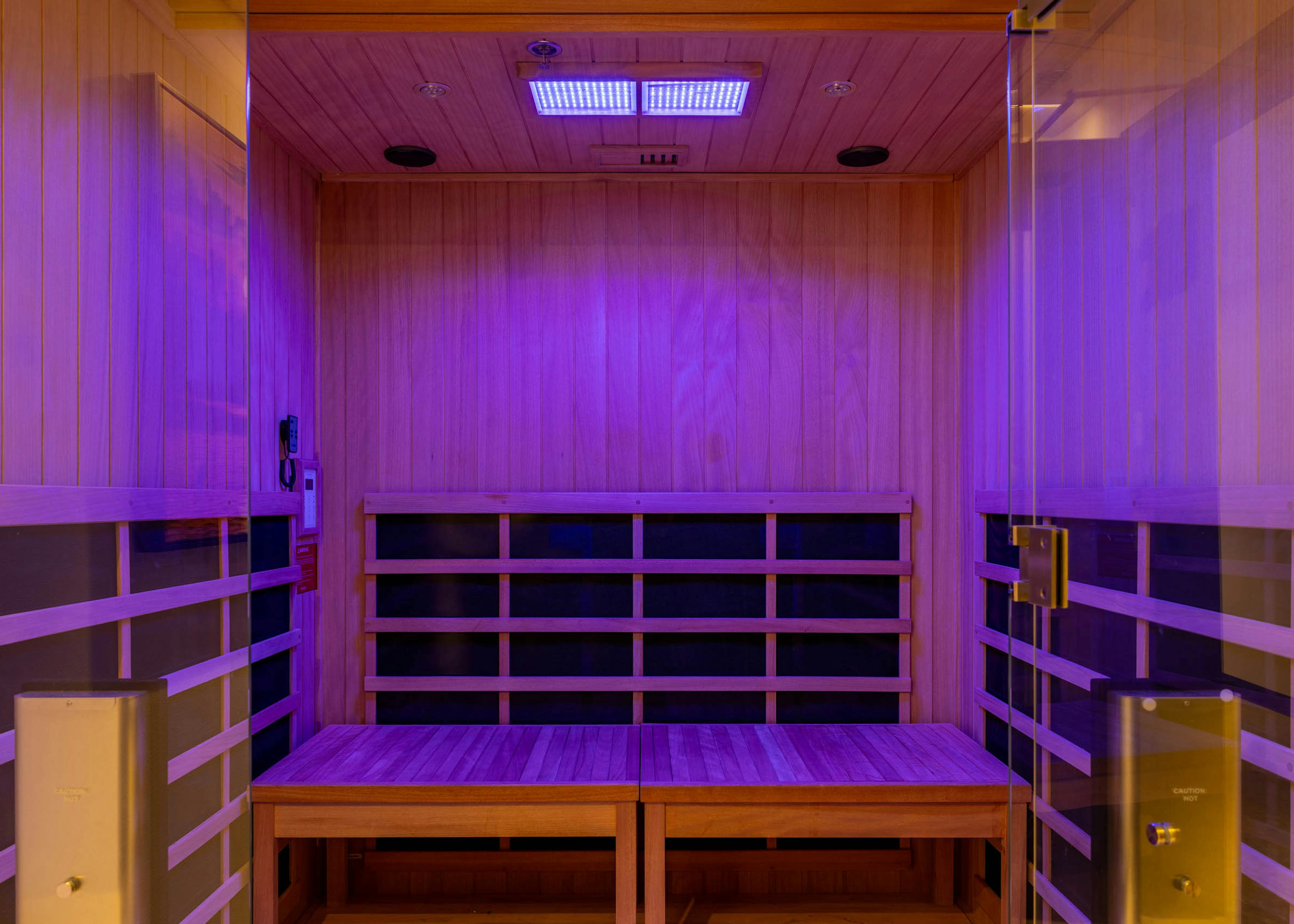Infrared sauna room at AMLI 535 apartments featuring natural wood interior, bench seating, and soft purple mood lighting.