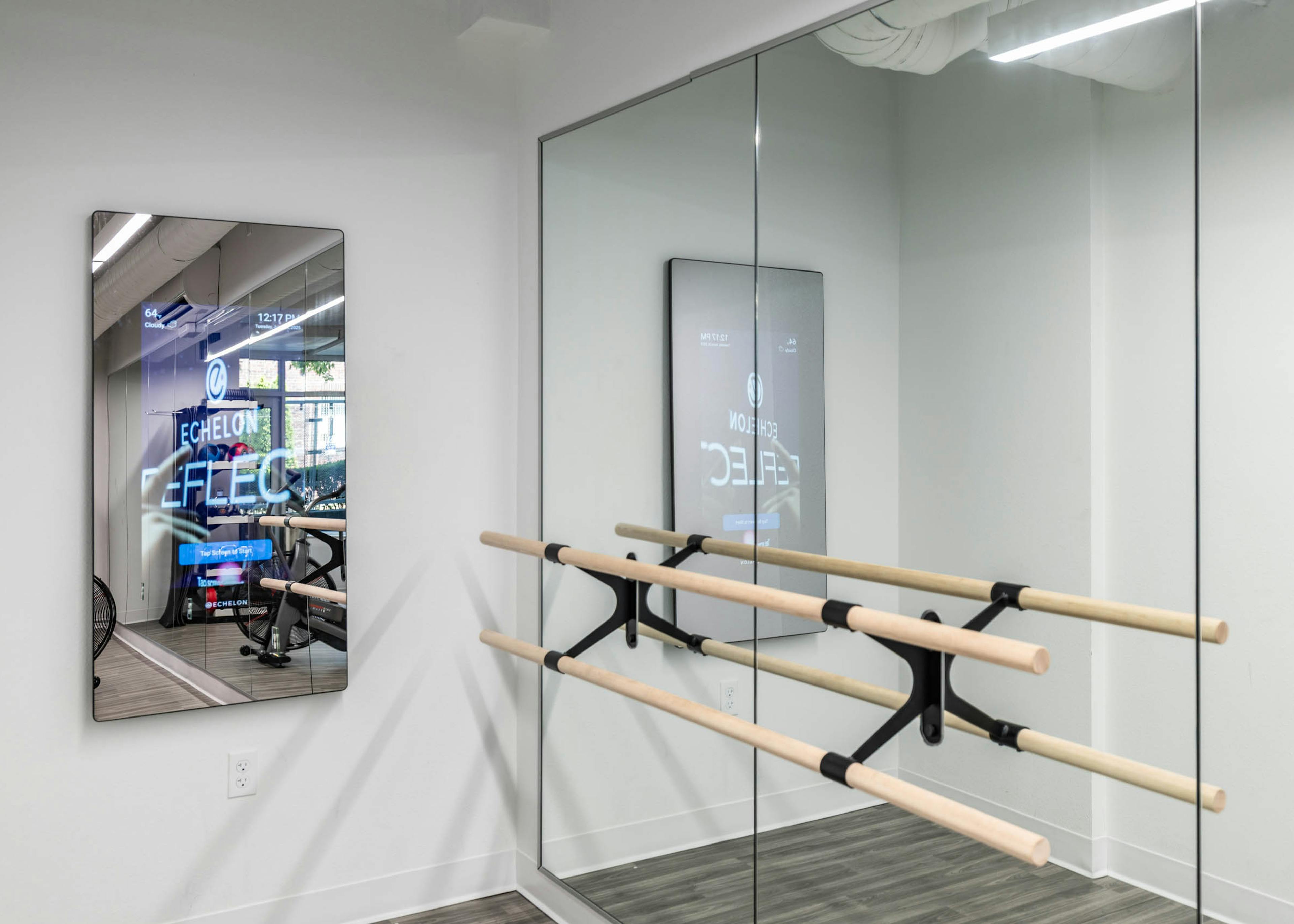 Workout studio at AMLI 535 apartments with ballet barre, mirrored walls, and interactive Echelon fitness mirror on white wall.