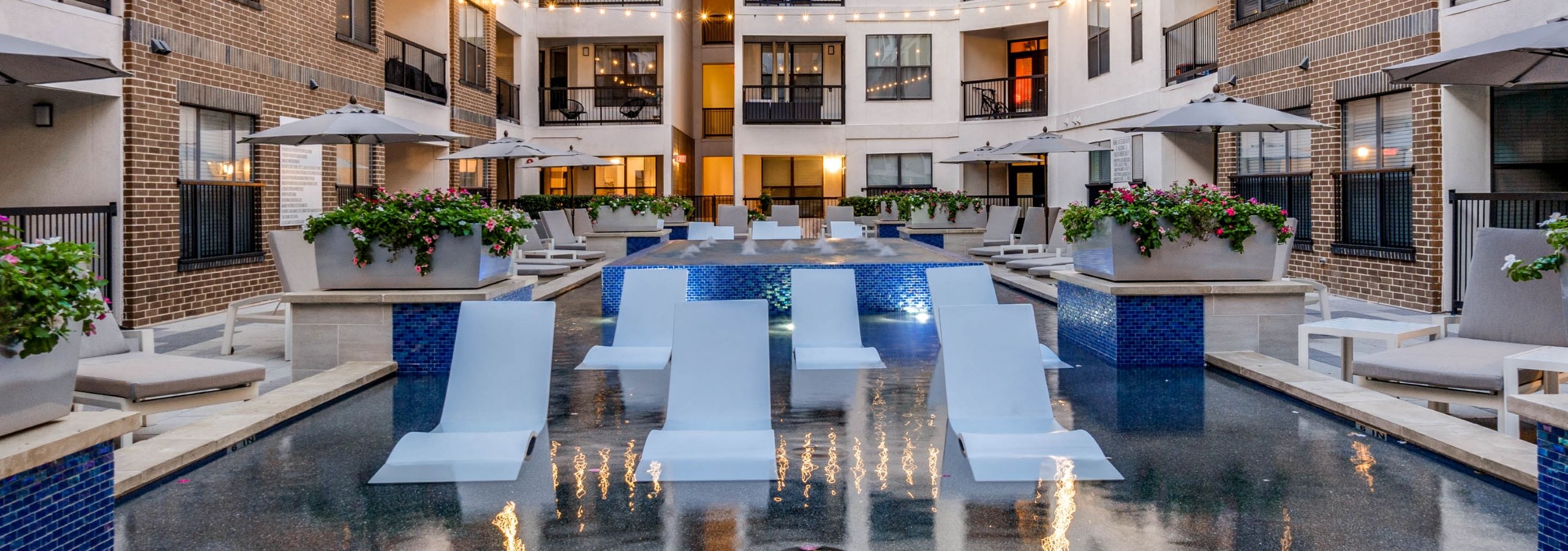 Courtyard with cooling spa at AMLI Quadrangle with white lounger chairs in the pool and apartments surrounding the chairs.