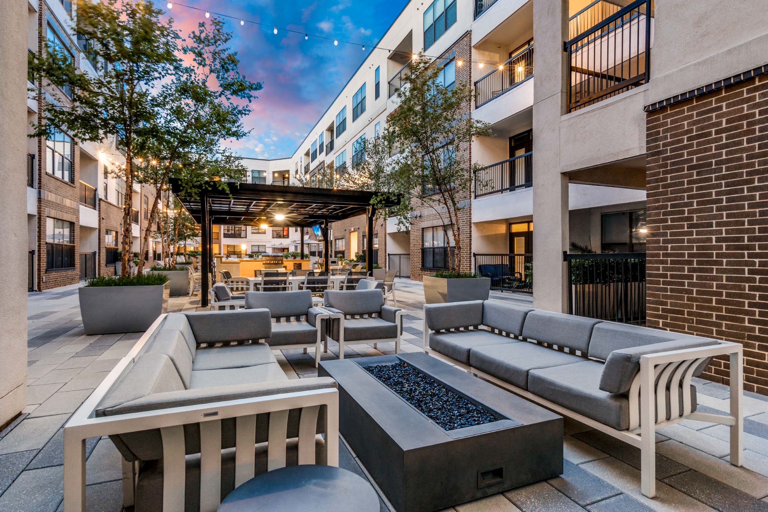 Courtyard couch seating at AMLI Quadrangle with rectangular firepit in the middle and pergola with grills in the background.