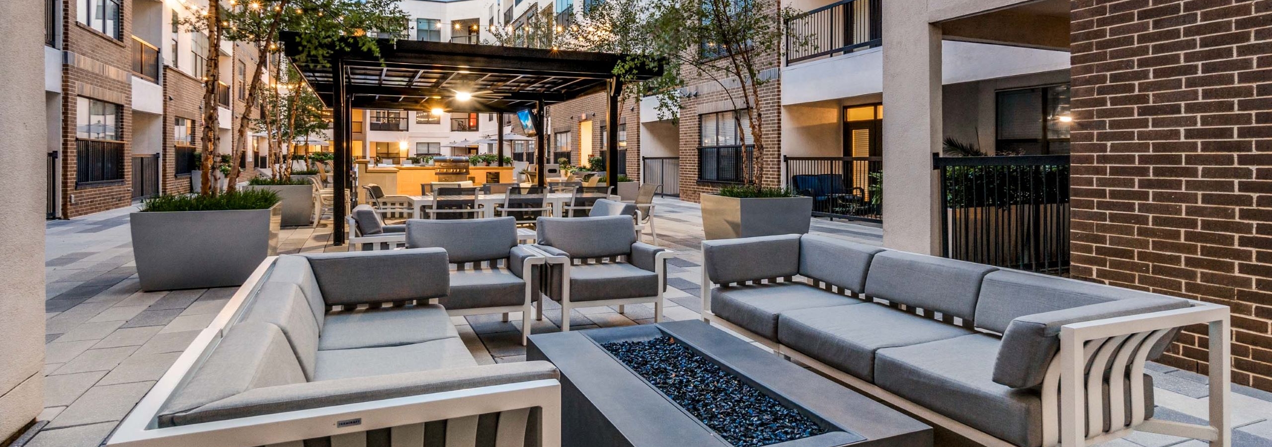 Courtyard couch seating at AMLI Quadrangle with rectangular firepit in the middle and pergola with grills in the background.