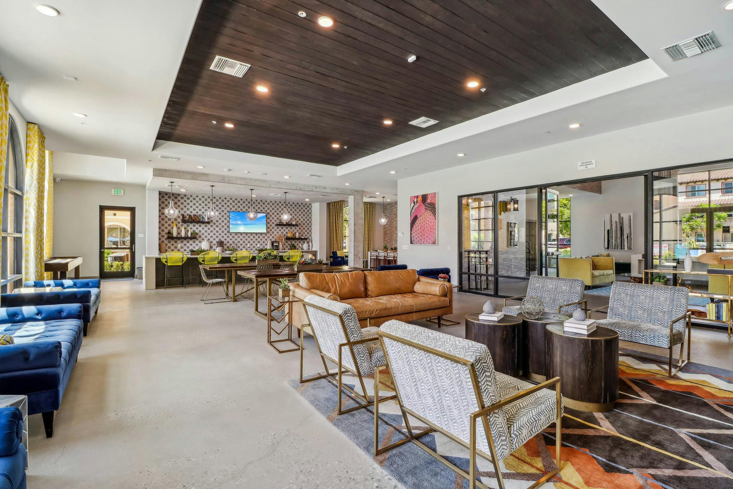 AMLI Camarillo apartment clubhouse with patterned rug, blue and leather seating, yellow barstools and a coffee bar along tiled wall