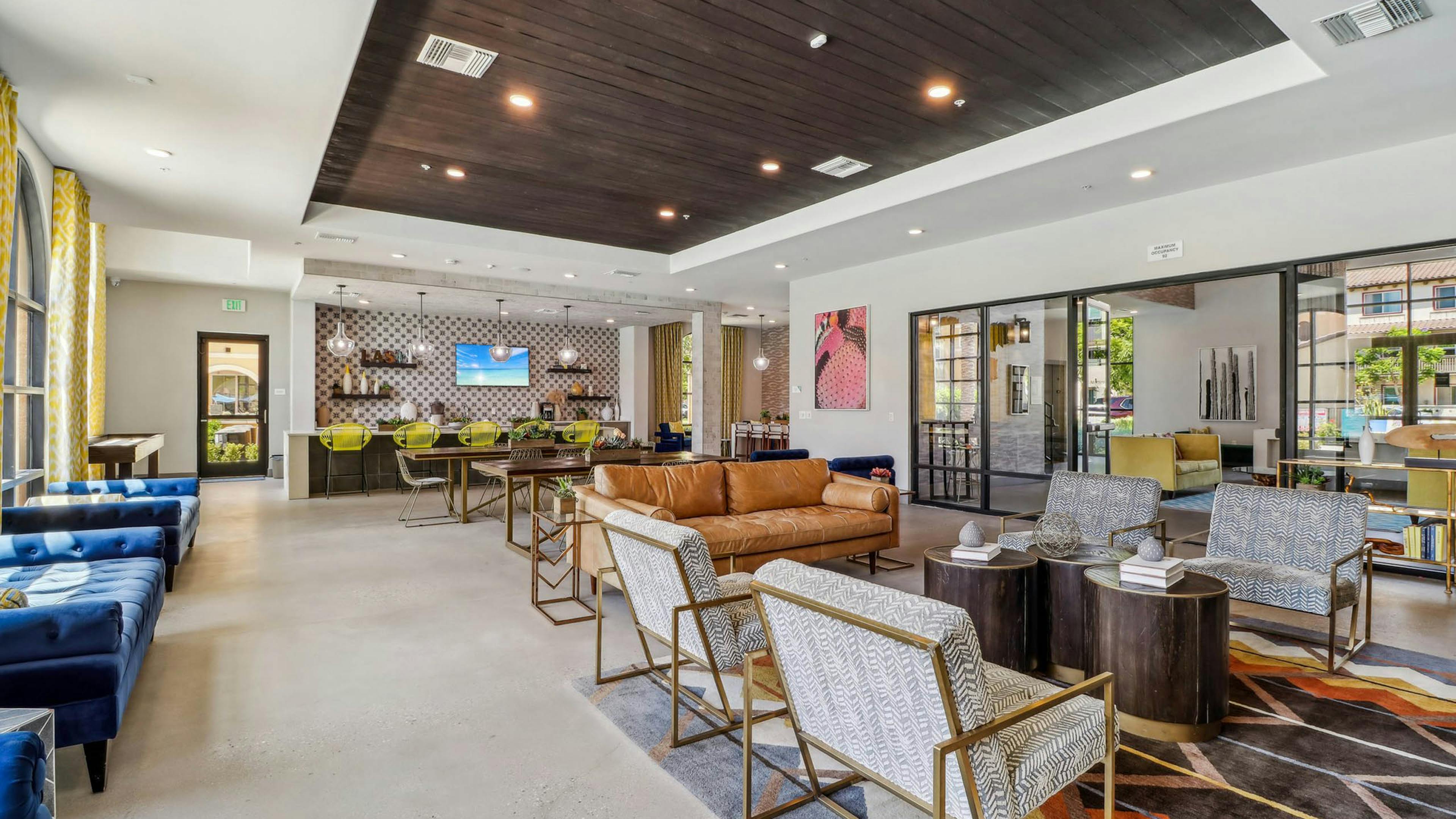 AMLI Camarillo apartment clubhouse with patterned rug, blue and leather seating, yellow barstools and a coffee bar along tiled wall