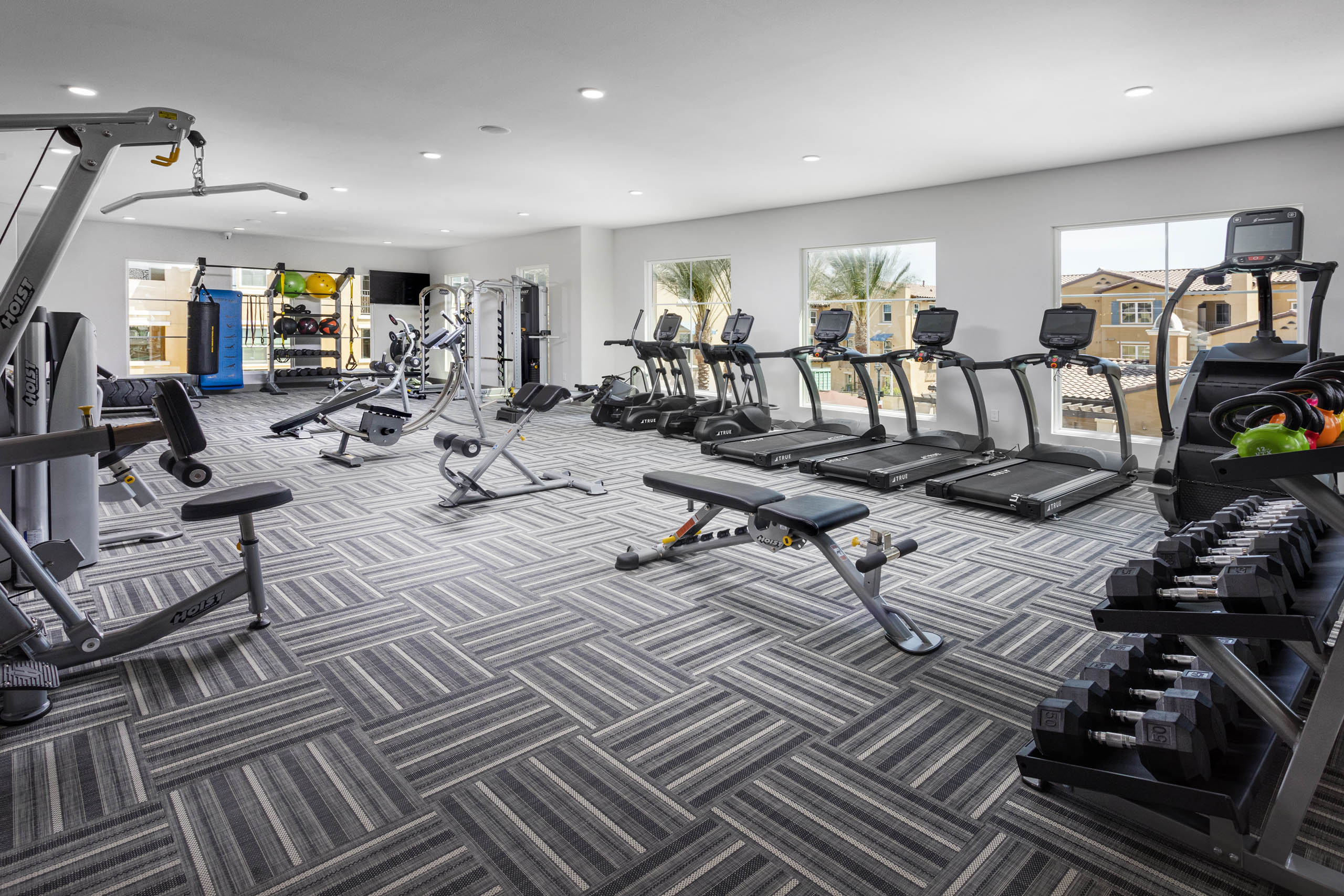 AMLI Camarillo fitness center with treadmills, strength equipment, punching bag and large windows overlooking the pool area