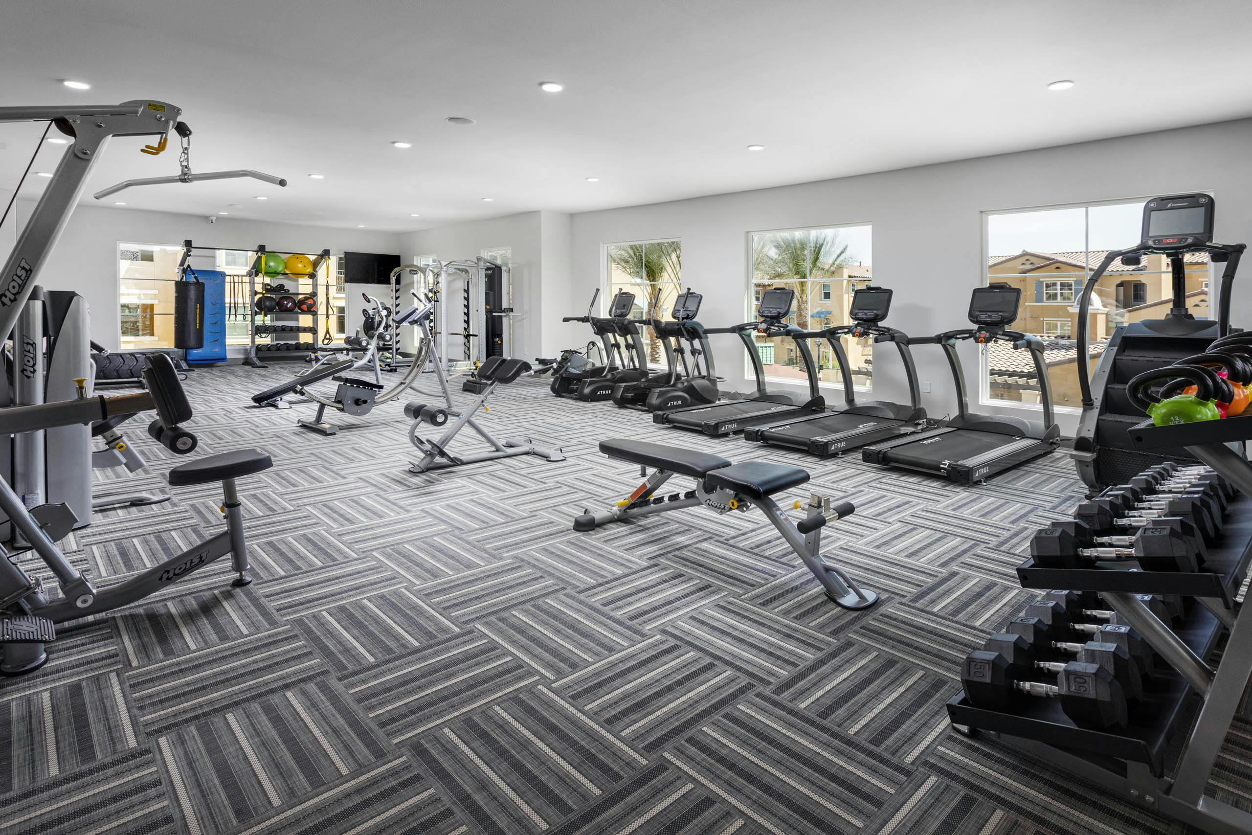AMLI Camarillo fitness center with treadmills, strength equipment, punching bag and large windows overlooking the pool area
